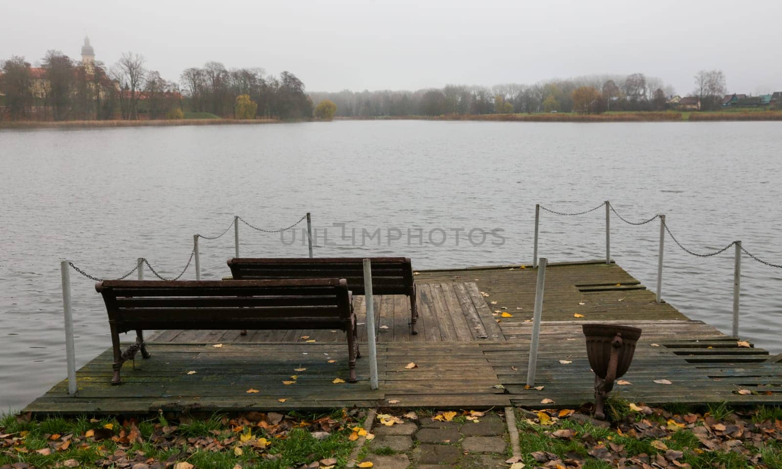 A place to rest on the bank of the river. Rustic pier against the background of the lake and forest in cloudy weather.