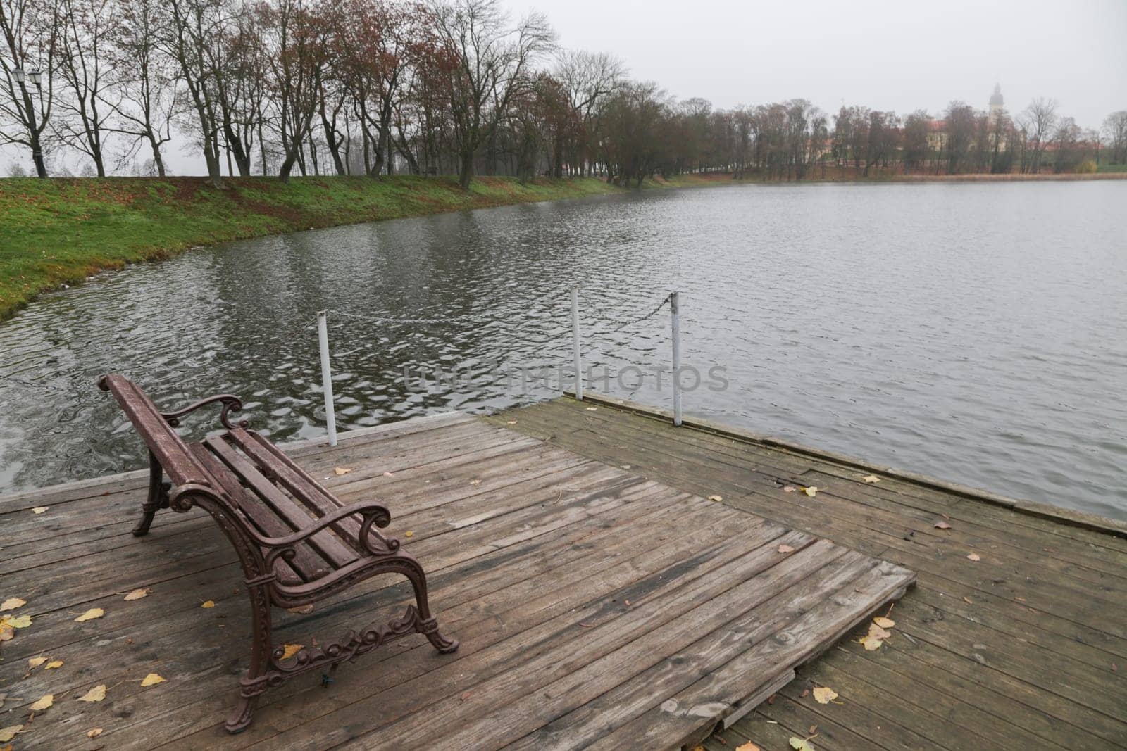 A place to rest on the bank of the river. Wooden pier on the background of the lake, autumn. Place for fishing, rural recreation, camping.