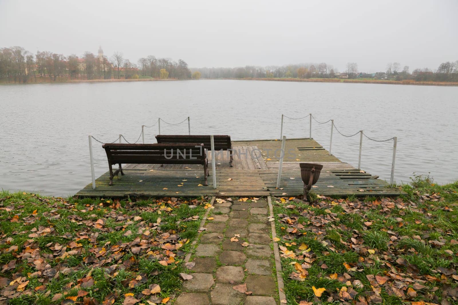 The benches on the wooden village pier. Wooden pier on the background of the lake, autumn. Place for fishing, rural recreation, camping.