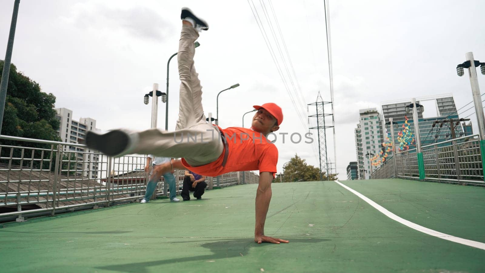 Young happy hipster perform break dancing or foot step with friend moving to hiphop music together. Skilled dancer doing freeze pose and waving hand. Modern lifestyle. Outdoor music 2024. Sprightly.