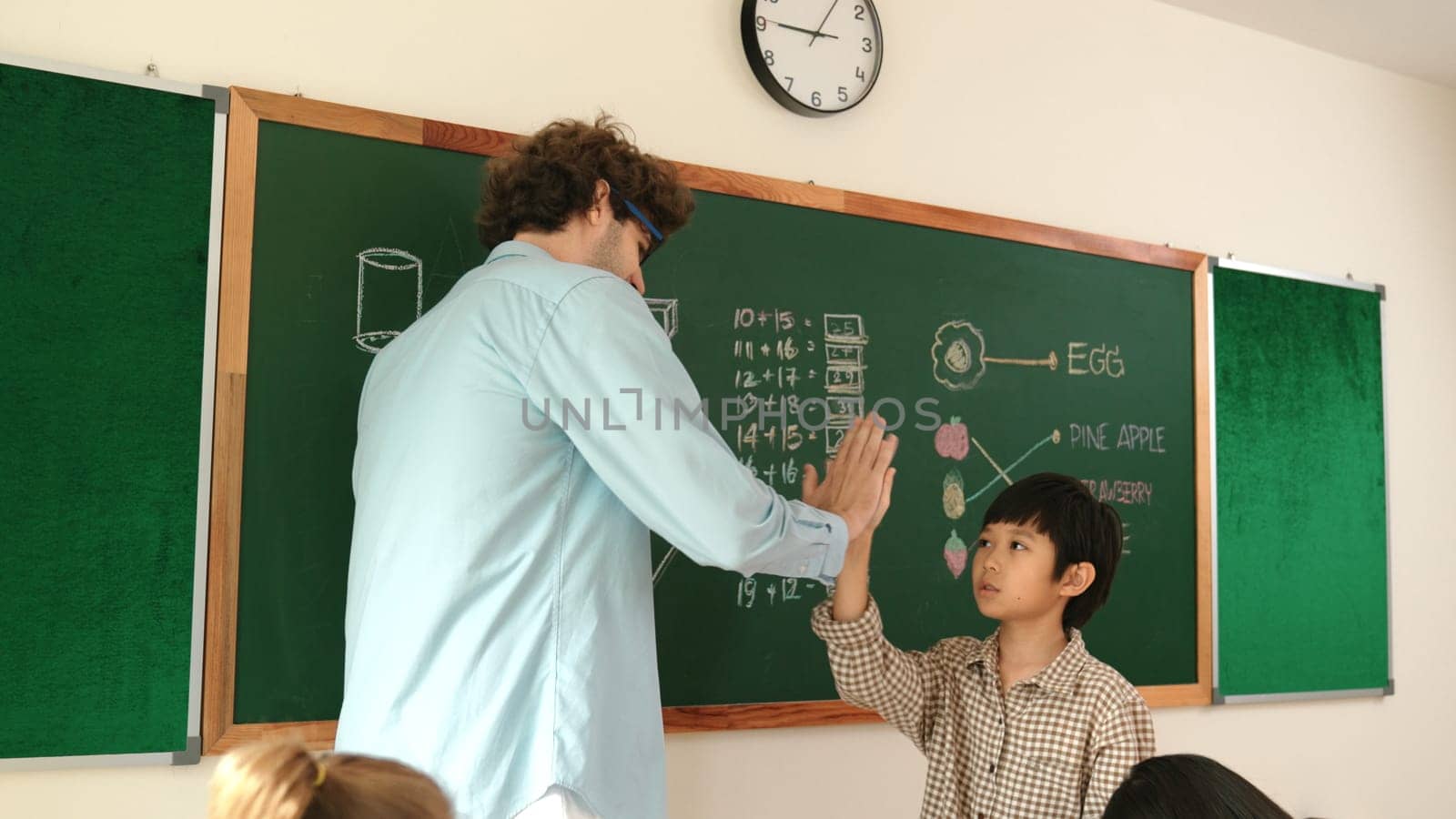 Boy write answer while teacher give high five to encourage child. Pedagogy. by biancoblue