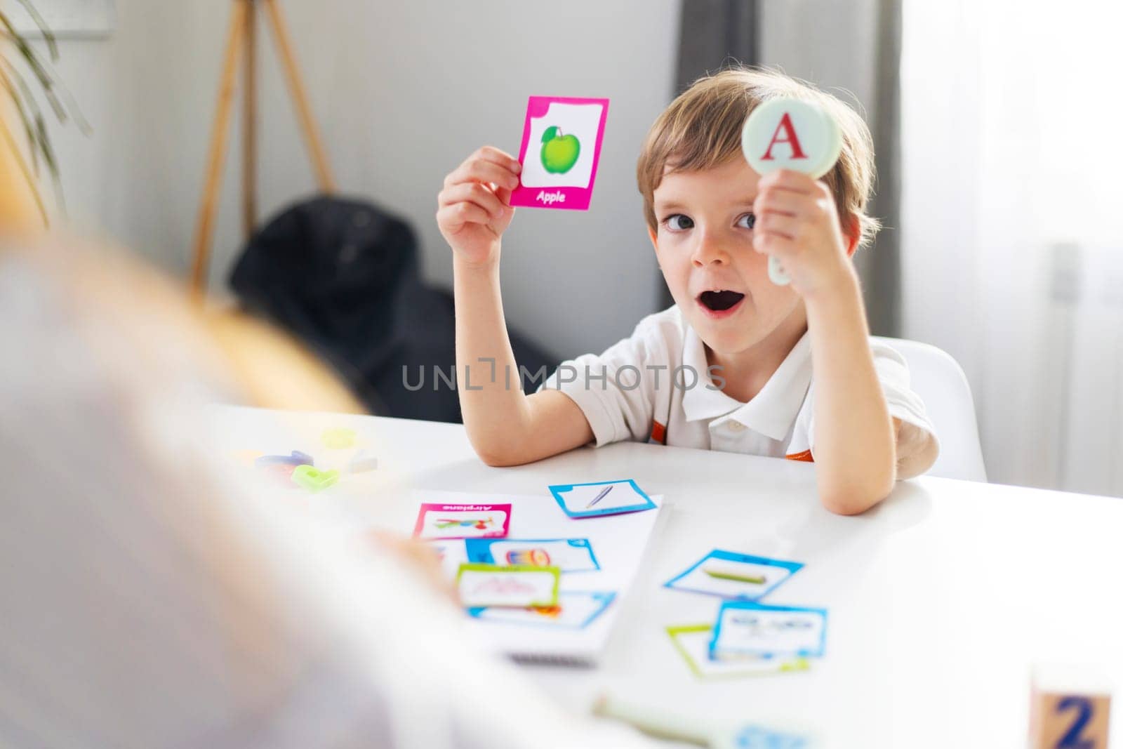 Young boy showing alphabet cards at home. Candid childhood learning concept. Design for education, poster, banner.