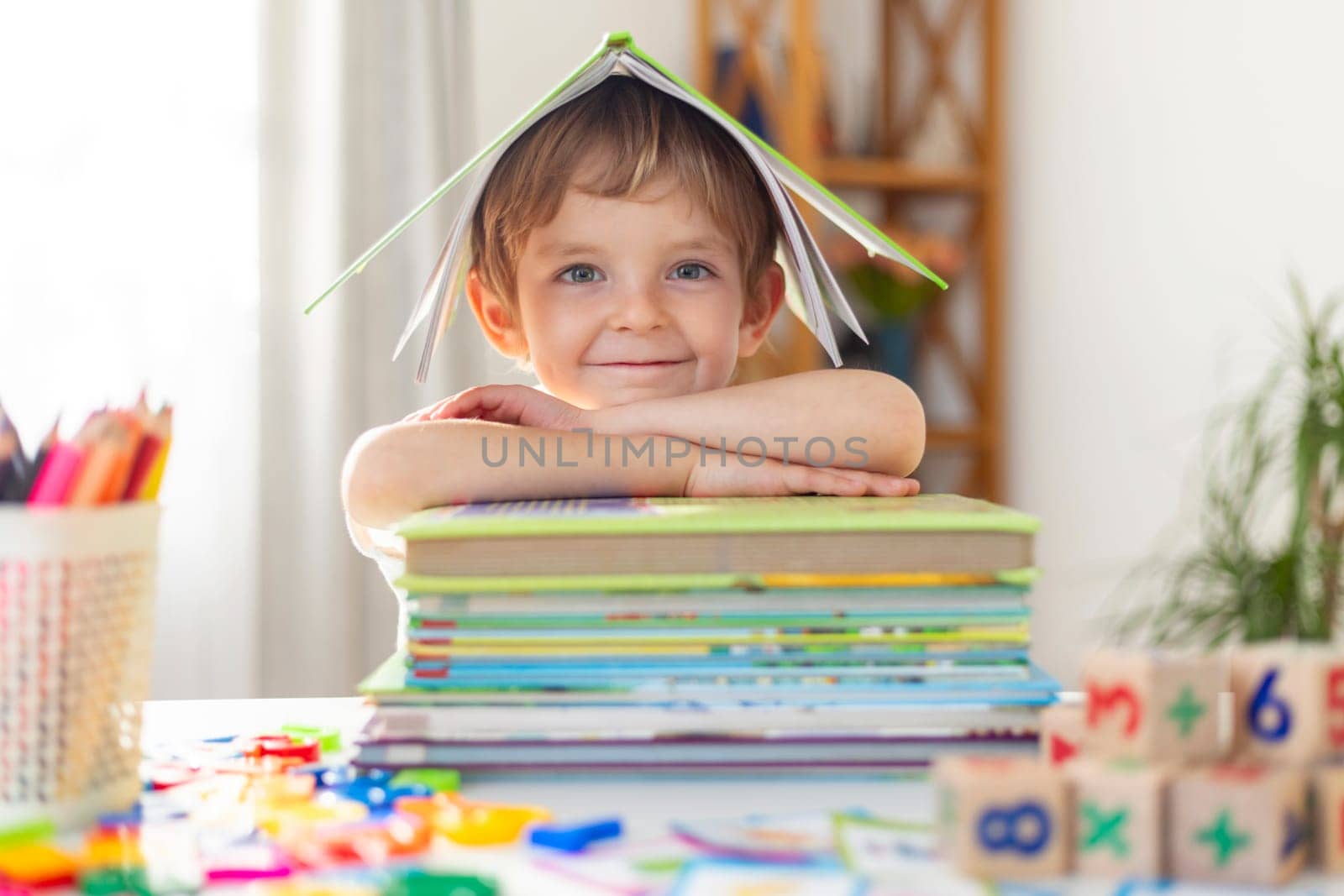 Cheerful boy with stack of books under paper roof. Joyful learning concept. Creative education and imagination theme. Design for educational poster, invitation to reading event, book club flyer.