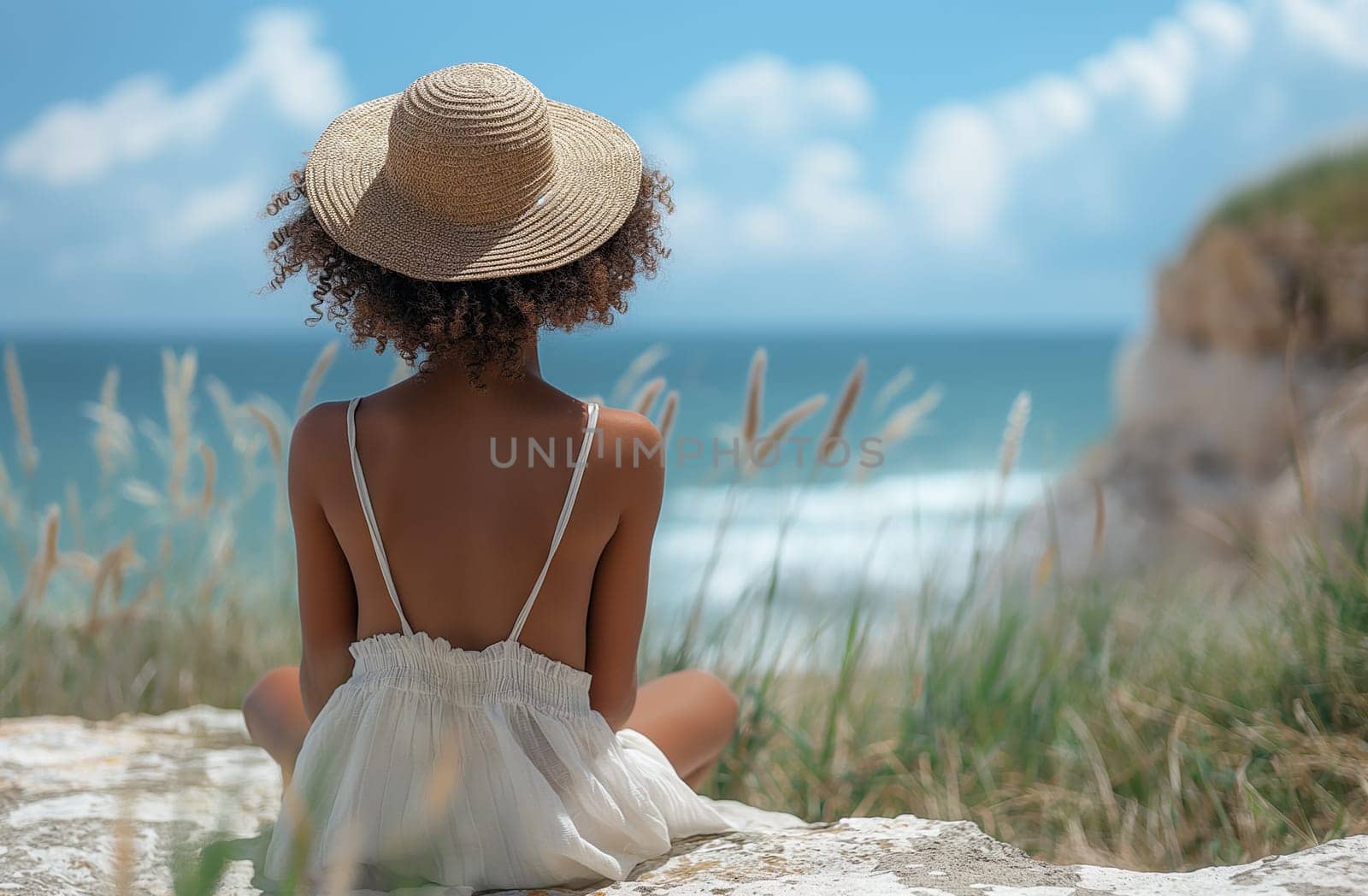 Black Woman in hat sitting peacefully on beachfront facing the ocean by Hype2art