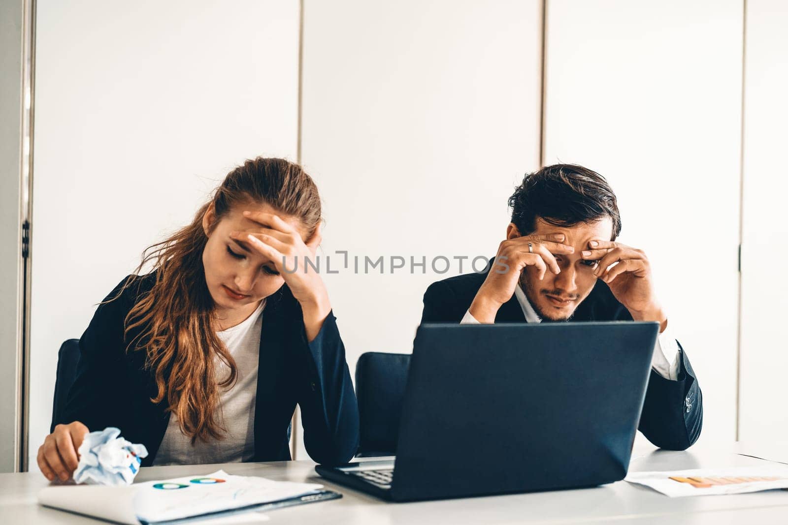 Unhappy serious businessman and businesswoman working using laptop computer on the office desk. Bad business crisis situation and bankruptcy concept. uds