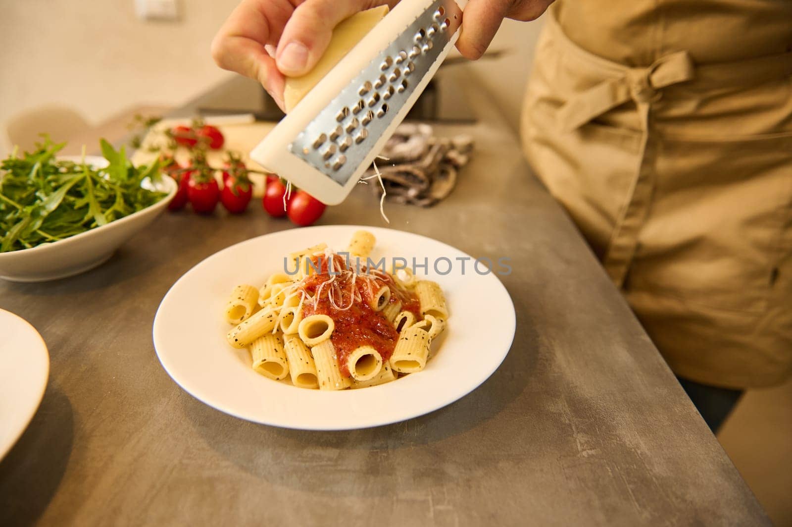 Male chef seasoning Italian pasta with grated cheese. Food background. Culinary. Epicure. Cooking. by artgf