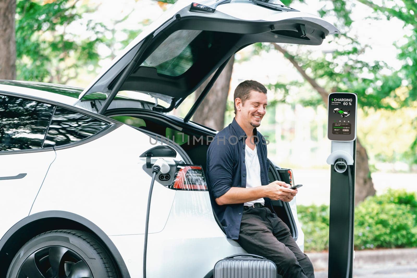 Man using smartphone to pay for electric car charging. Exalt by biancoblue