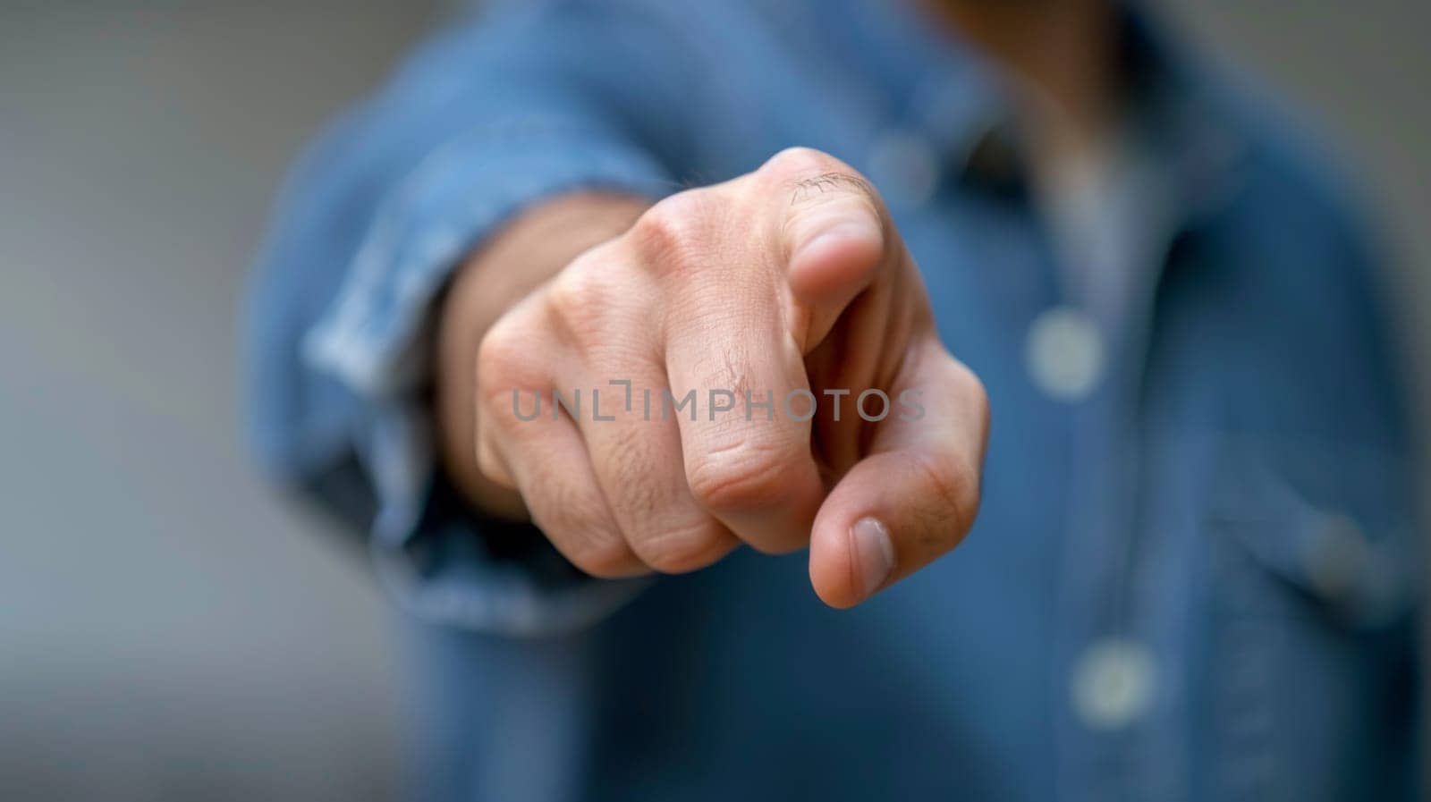A man in a blue shirt pointing at something with his finger