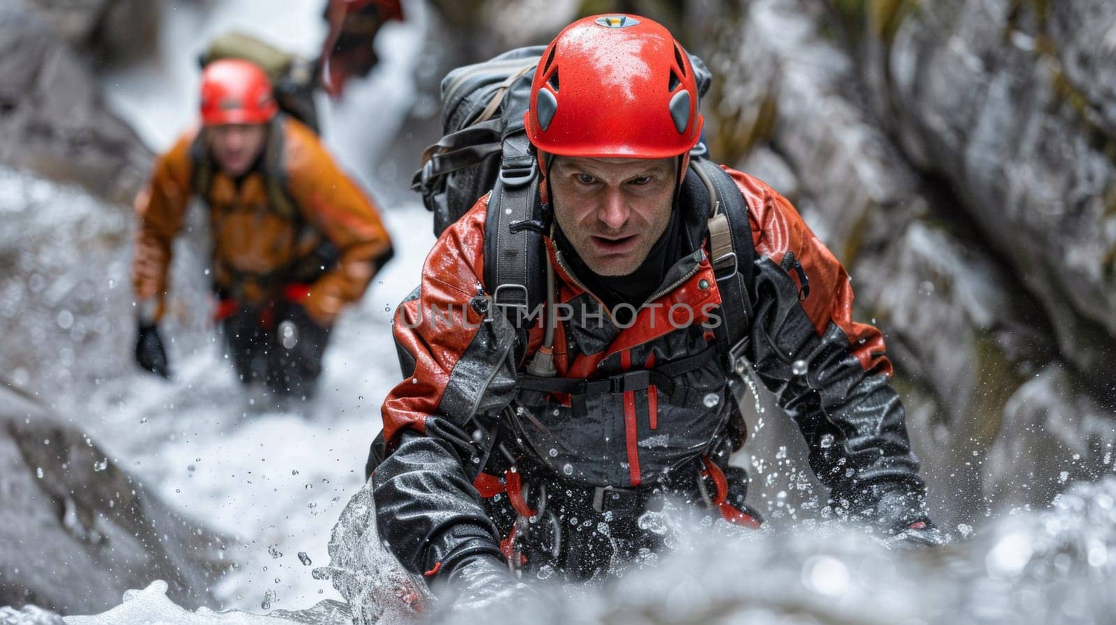 A group of a man wearing an orange helmet and red jacket is climbing up rocks