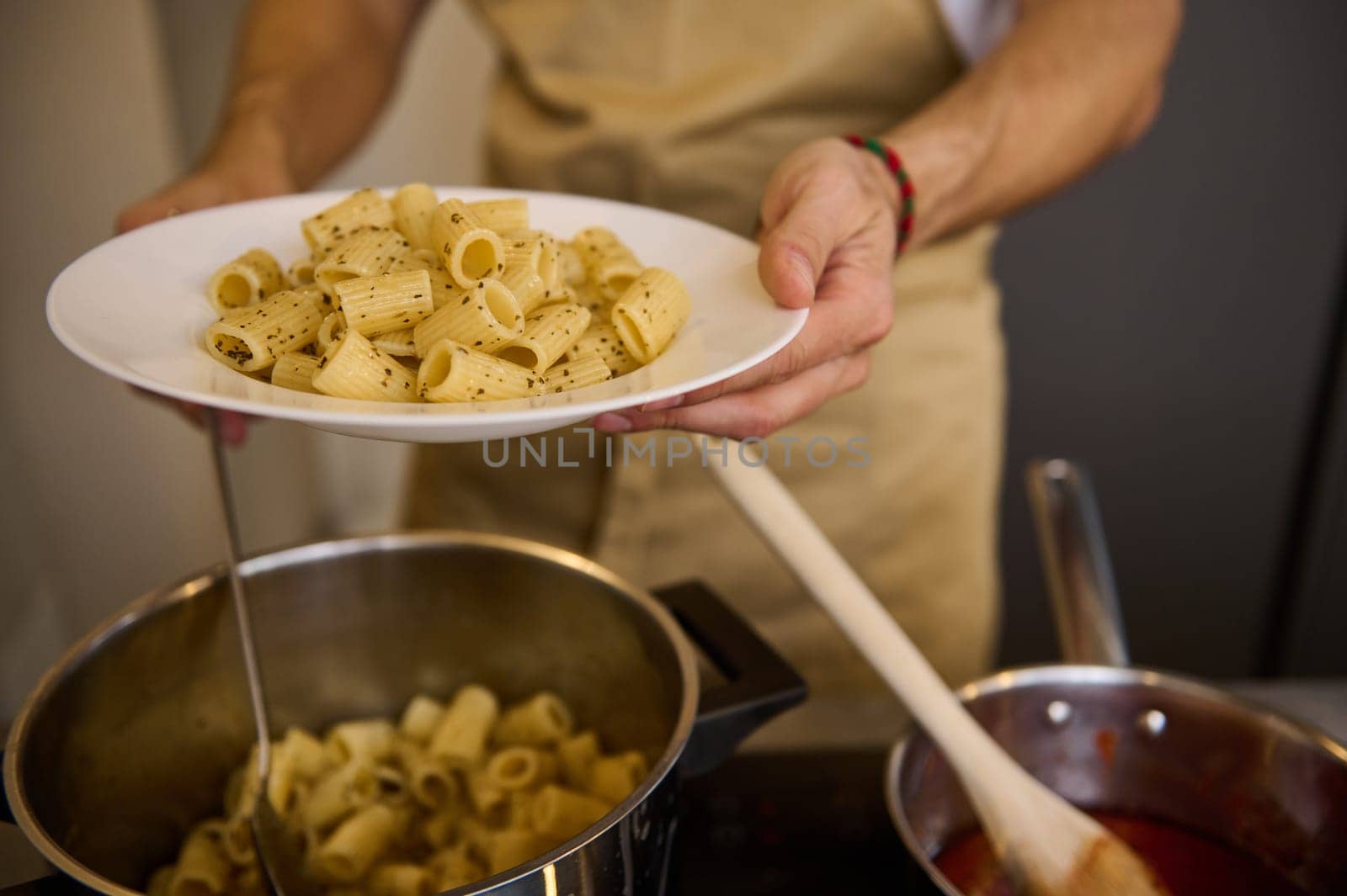 Close-up of a chef plating up Italian pasta before serving to customers.