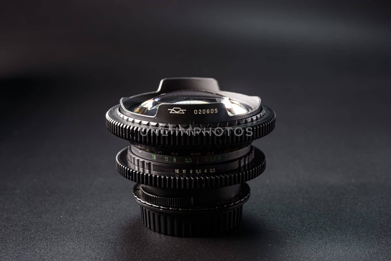 Stacked vintage camera lenses with a focus on the serial number, reflective glass surface, photography tools against a dark gradient background. by mosfet_ua