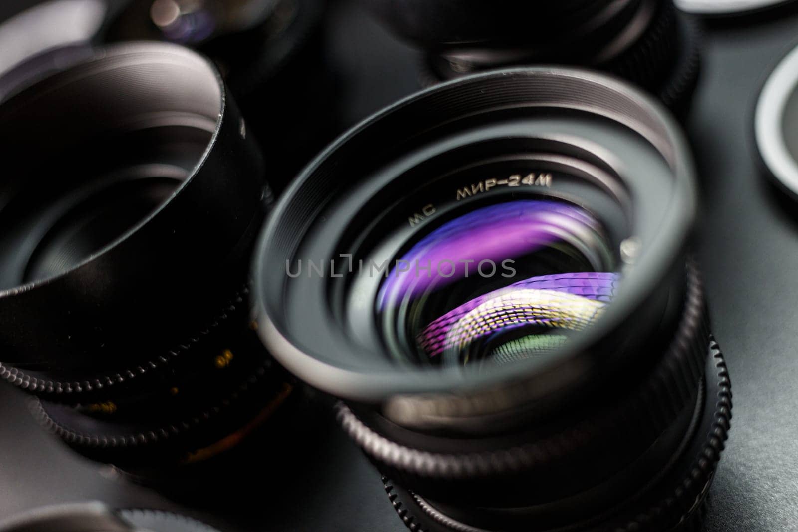 Vivid reflection on the glass of a vintage MC lens, detailed view of photographic collection, lenses in soft focus in the background by mosfet_ua