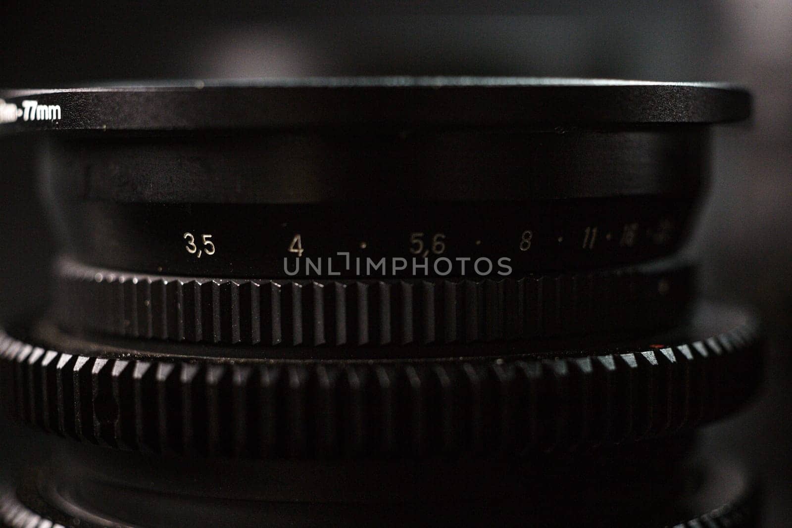 Detailed shot of aperture scale on lens, 17mm indication, focus adjustment markings for photographers, against dark, textured backdrop.