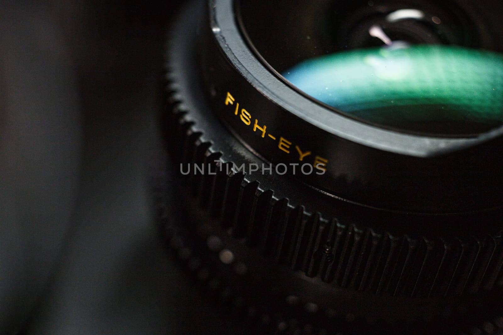 Close-up of fisheye lens with distinct yellow lettering, capturing unique photography perspectives, set against a dark, blurred background by mosfet_ua