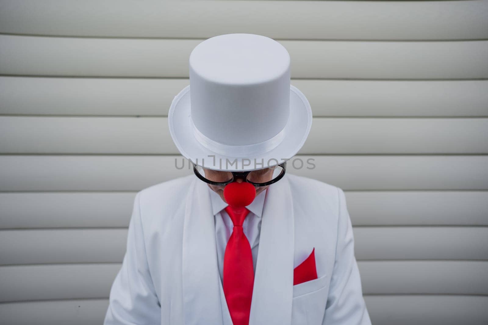 Portrait of a clown in a white classic suit and a vintage high hat