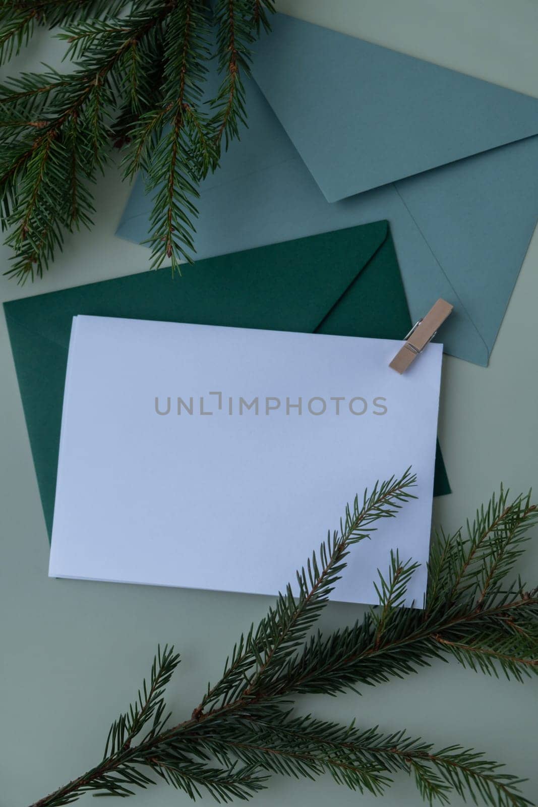 Empty paper letter envelope note Copy space Christmas mockup for lettering art drawing with fir branches on pastel green background. Letter to Santa Claus concept. Flat lay, top view