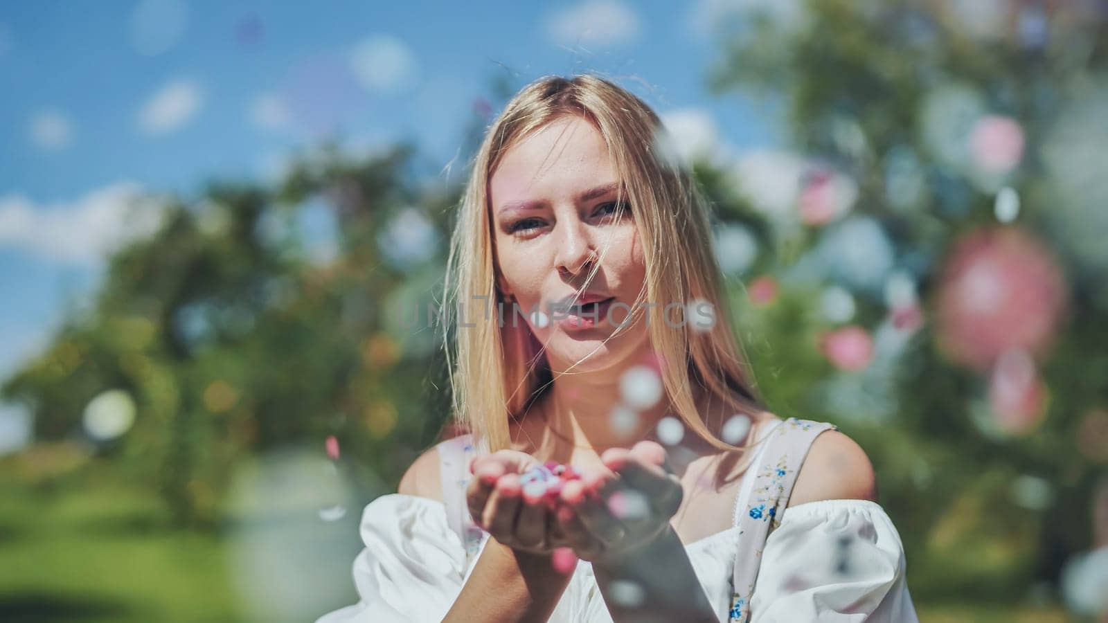 A girl blows a multi-coloured paper confetti out of her hands