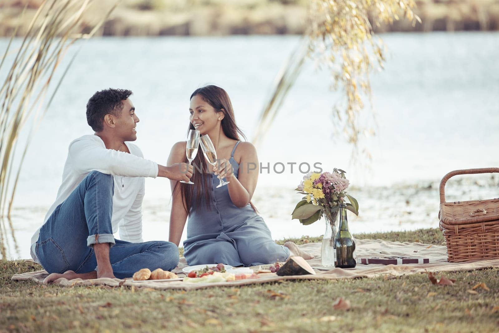 Man, woman and date with picnic, wine and romance for love or relationship anniversary. Couple, nature and lake with alcohol, happiness and summer passion with bouquet and flowers for celebration.