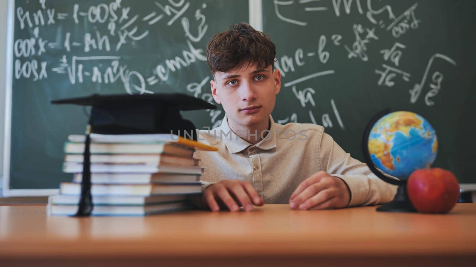 Portrait of a high school student against a background of blackboard, globe and books with cap. by DovidPro