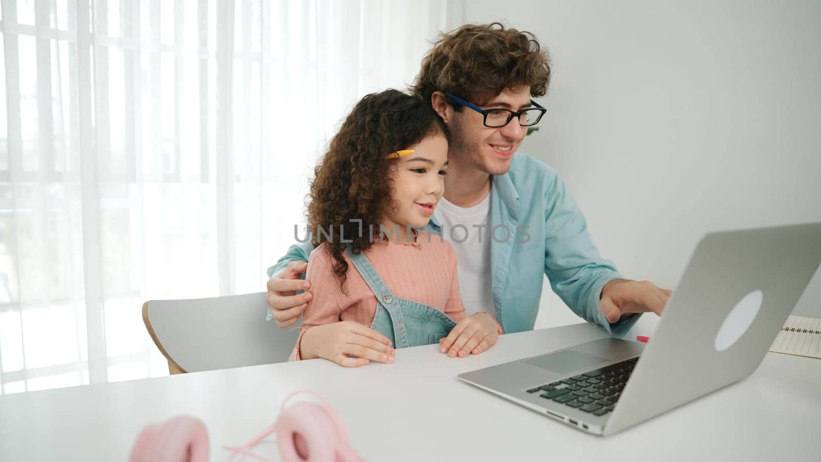 Father explain generate AI while american girl looking at screen. Attractive caucasian dad teaching daughter learning coding engineering prompt and programing system at table with headphone. Pedagogy.