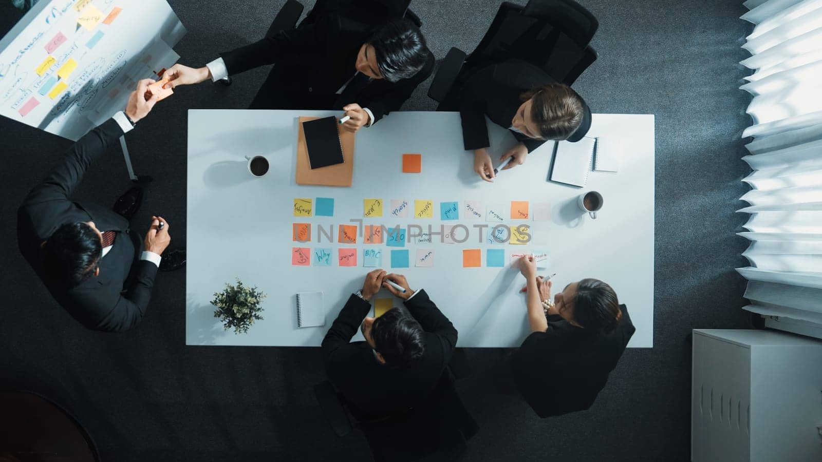 Top down aerial view of manager standing and present marketing plan to skilled investor. Diverse business team working together to analyze financial statistic graph at meeting table. Directorate.