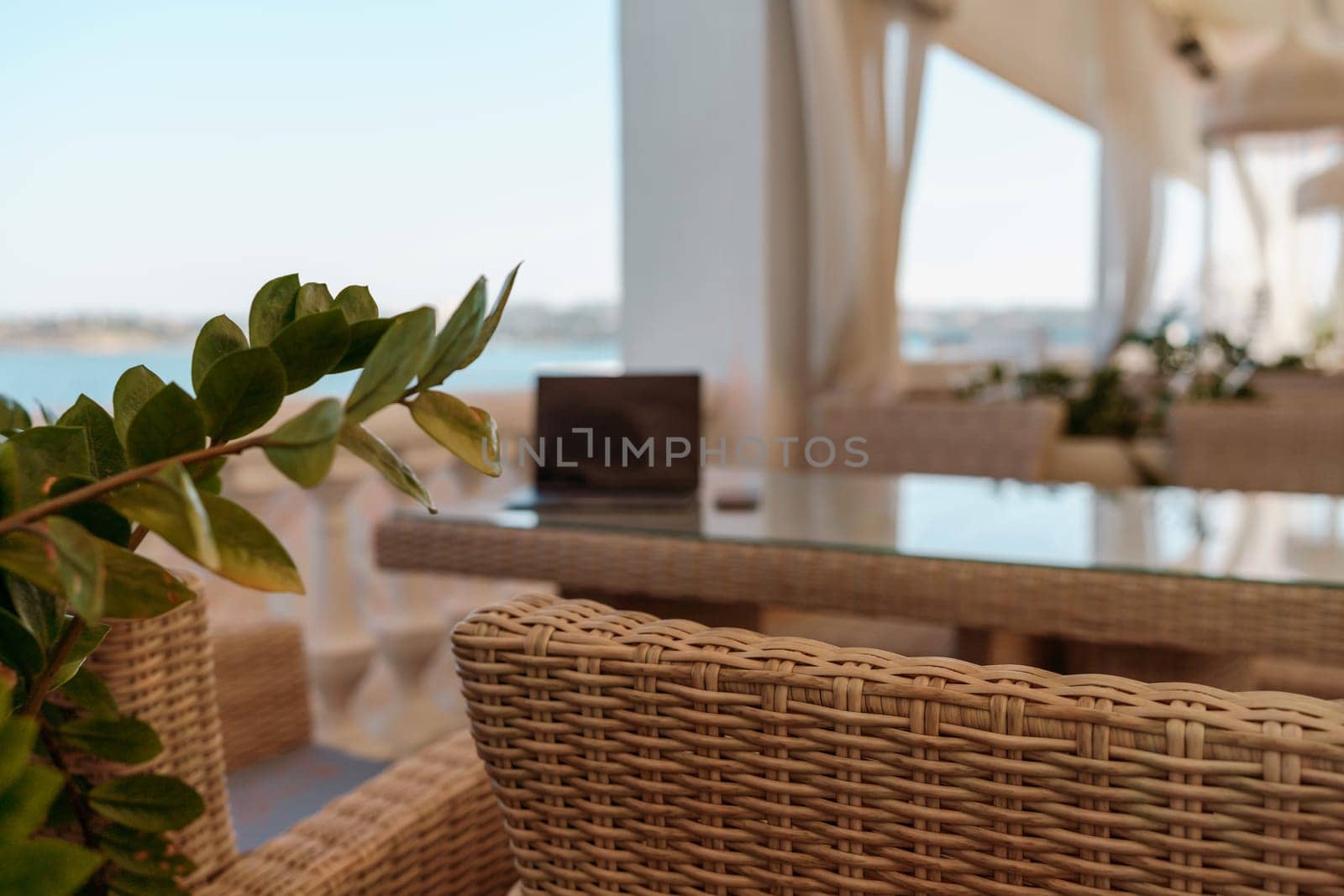 Wicker furniture tables in the open air are waiting for visitors. The interior of the restaurant in the open air. Empty tables of street cafe. by Matiunina