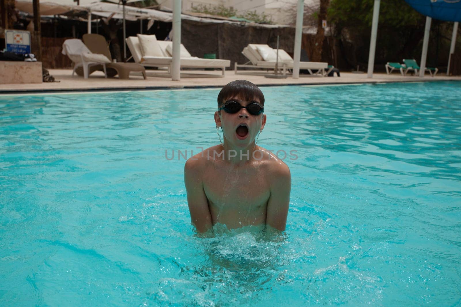 Boy with glasses swims in the pool by gordiza