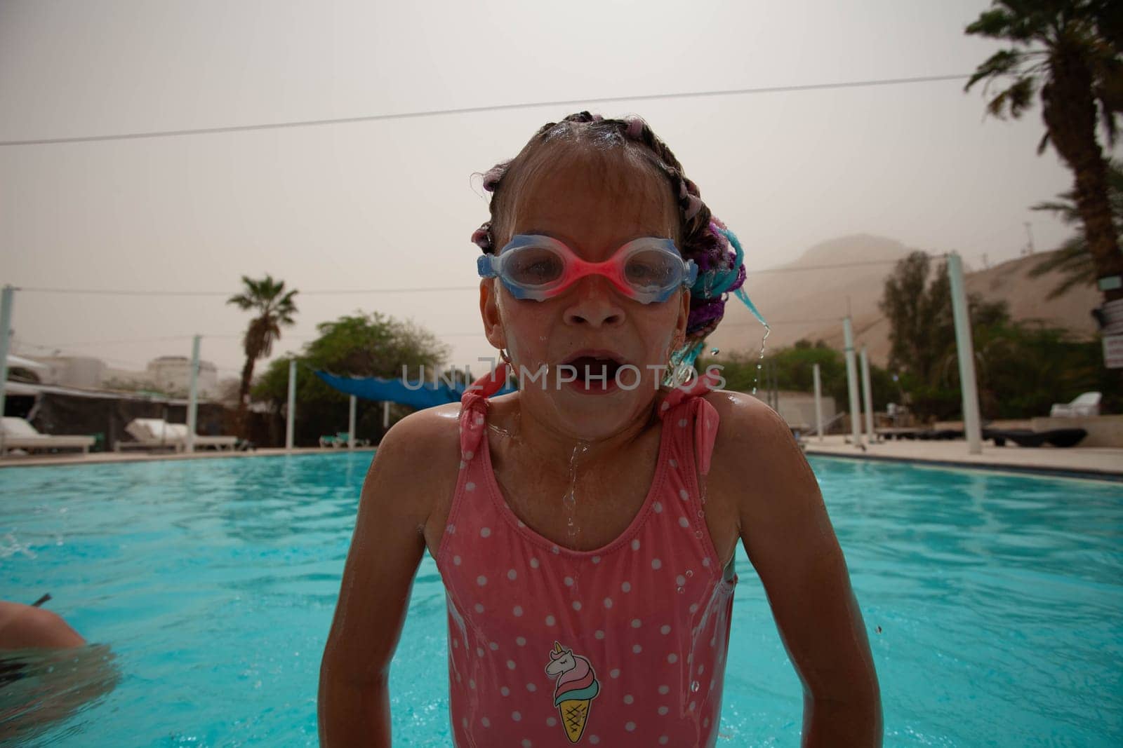 A girl with glasses and bright pigtails swims in the pool. High quality photo