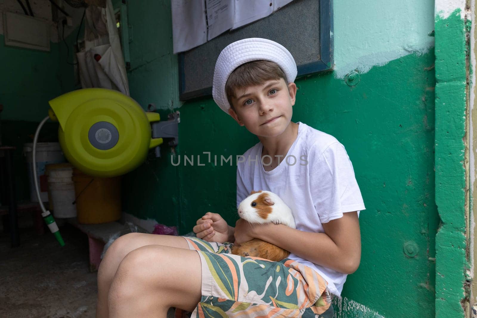 Boy holding a guinea pig in his arms by gordiza