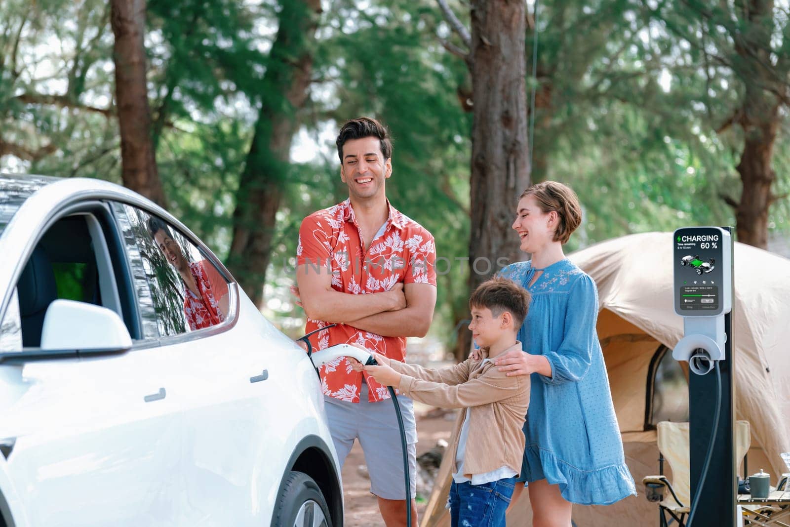 Outdoor adventure and family vacation camping in nature travel by eco friendly car for sustainable future. Lovely family recharge EV car with EV charging station in campsite. Perpetual