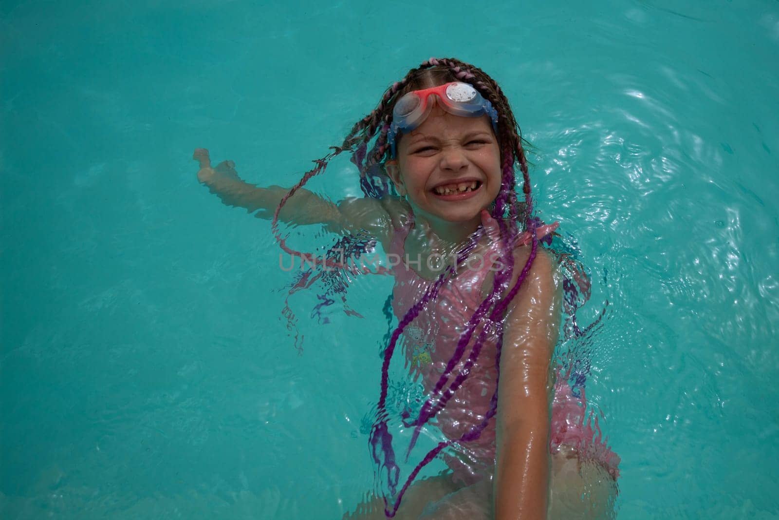 A girl with glasses and bright pigtails swims in the pool by gordiza