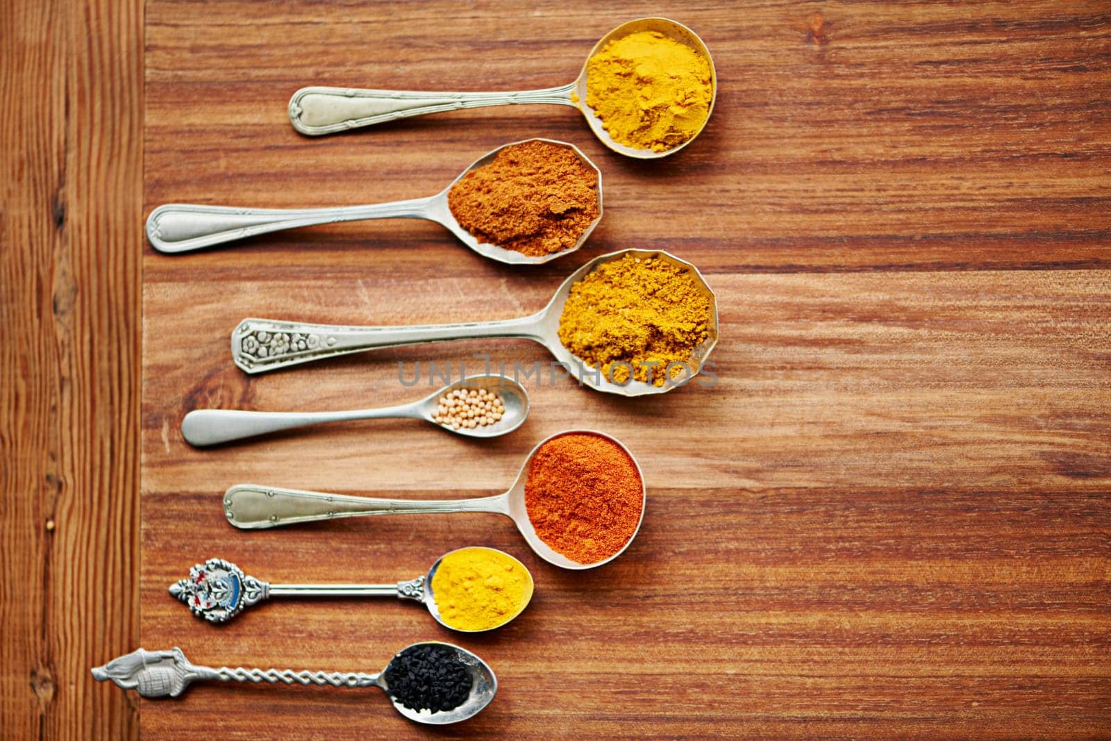 Colour, curry and spices on vintage spoon with natural ingredients to cook dinner. Asian, power and seasonings for hot, spicy and delicious authentic Indian food with flavour on tabletop in kitchen.
