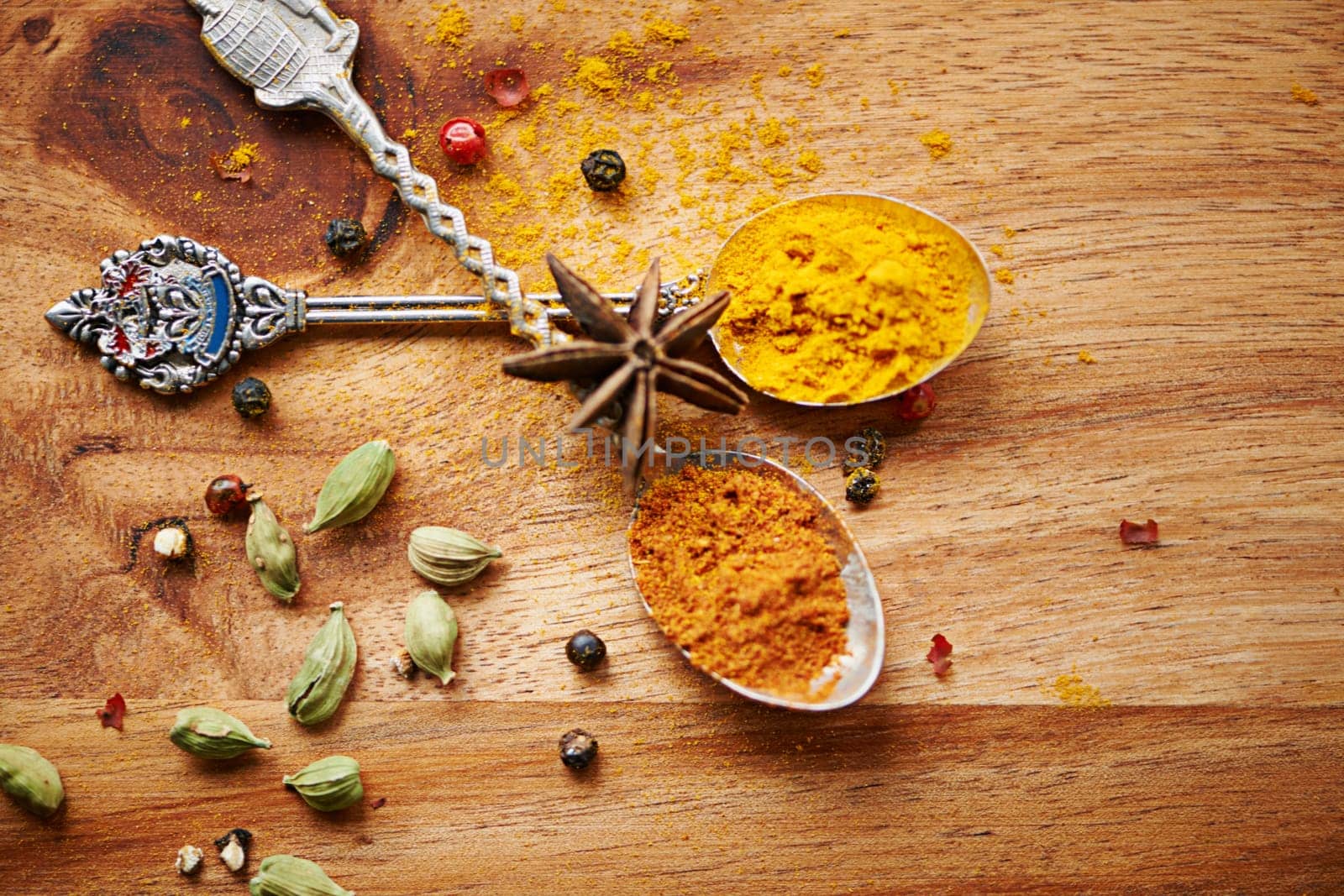Spoons, spice and selection of seasoning for cooking on kitchen table, turmeric and cardamom for meal. Top view, condiments and options for spicy gourmet in Indian culture, art and food preparation.