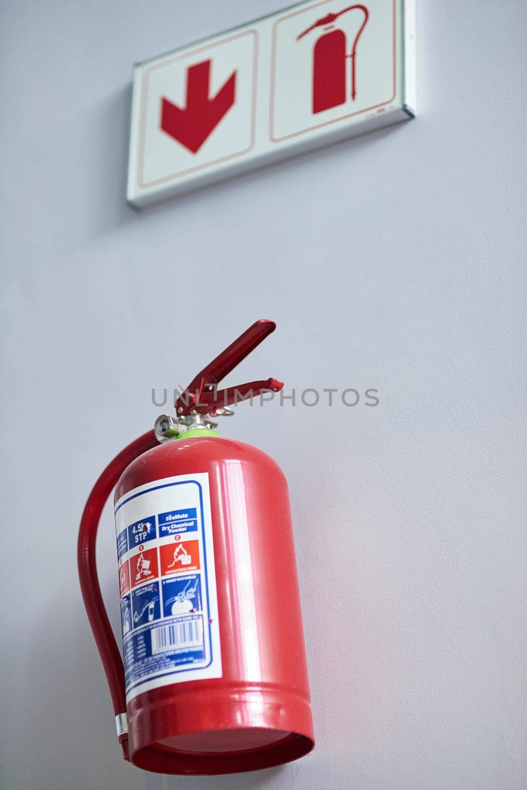 Fire extinguisher, wall and sign for firefighting, action and safety with emergency help and support. Portable dry and chemical powder to stop flame, air and oxygen for building equipment and arrow.