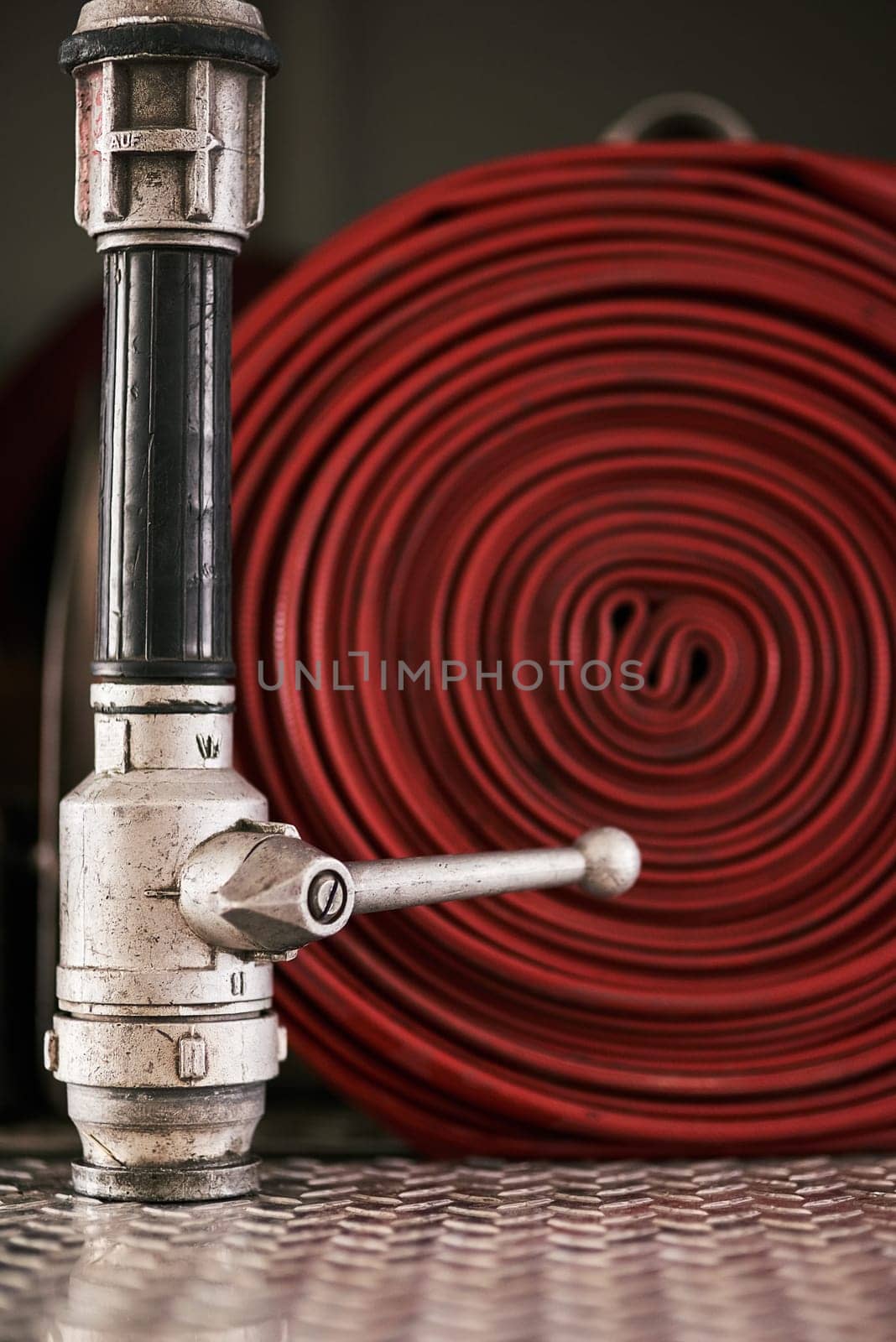 Emergency, equipment and pipe with red fire hose for security, danger or health and safety at station. Closeup of gear, tool or pressure extingusher ready in rescue, service or firefighting operation by YuriArcurs