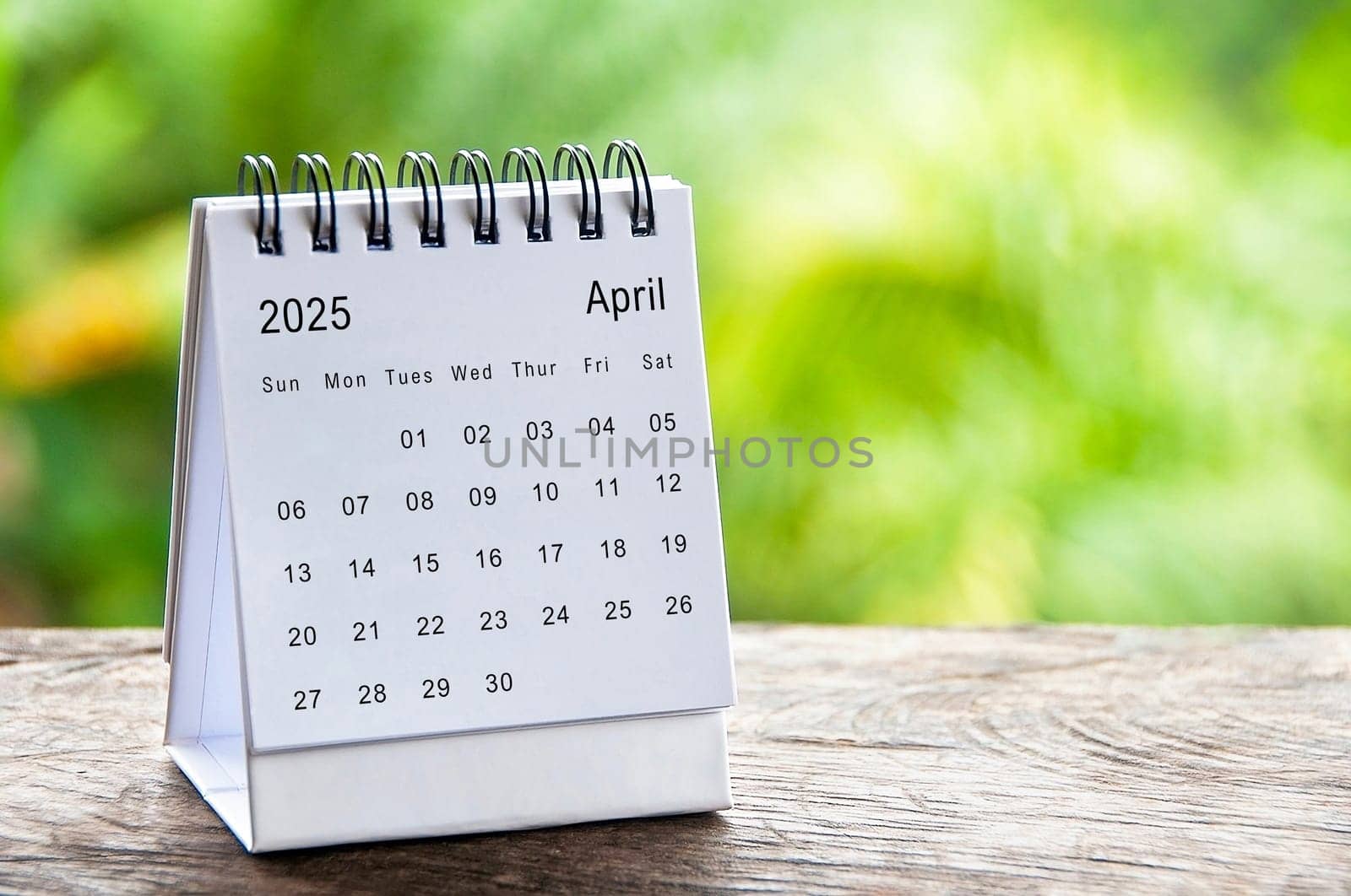 April 2025 white table calendar with customizable space for text. Calendar concept and copy space