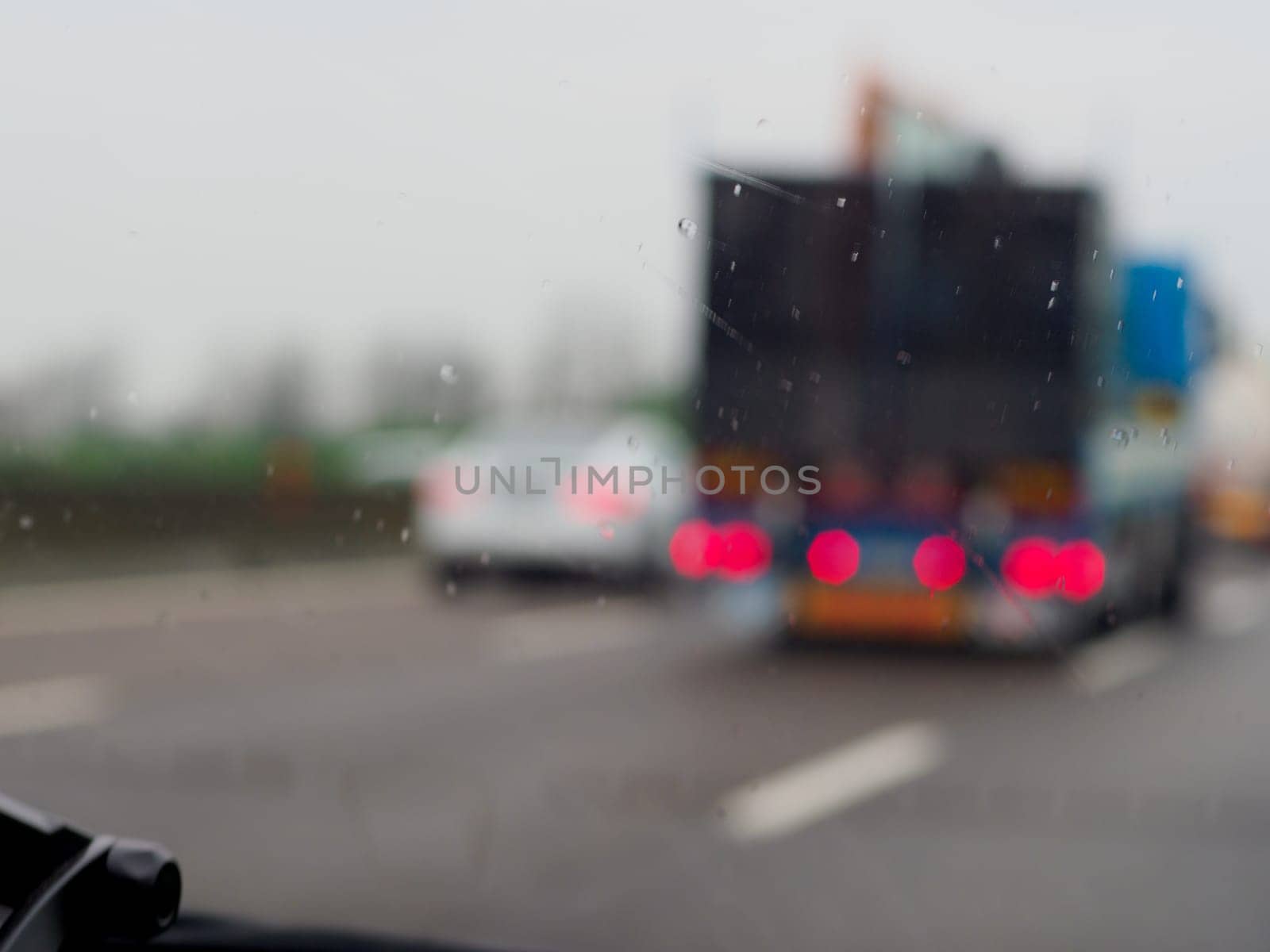 A blurry image of a busy expressway with cars and a truck under a storm rainy day by verbano