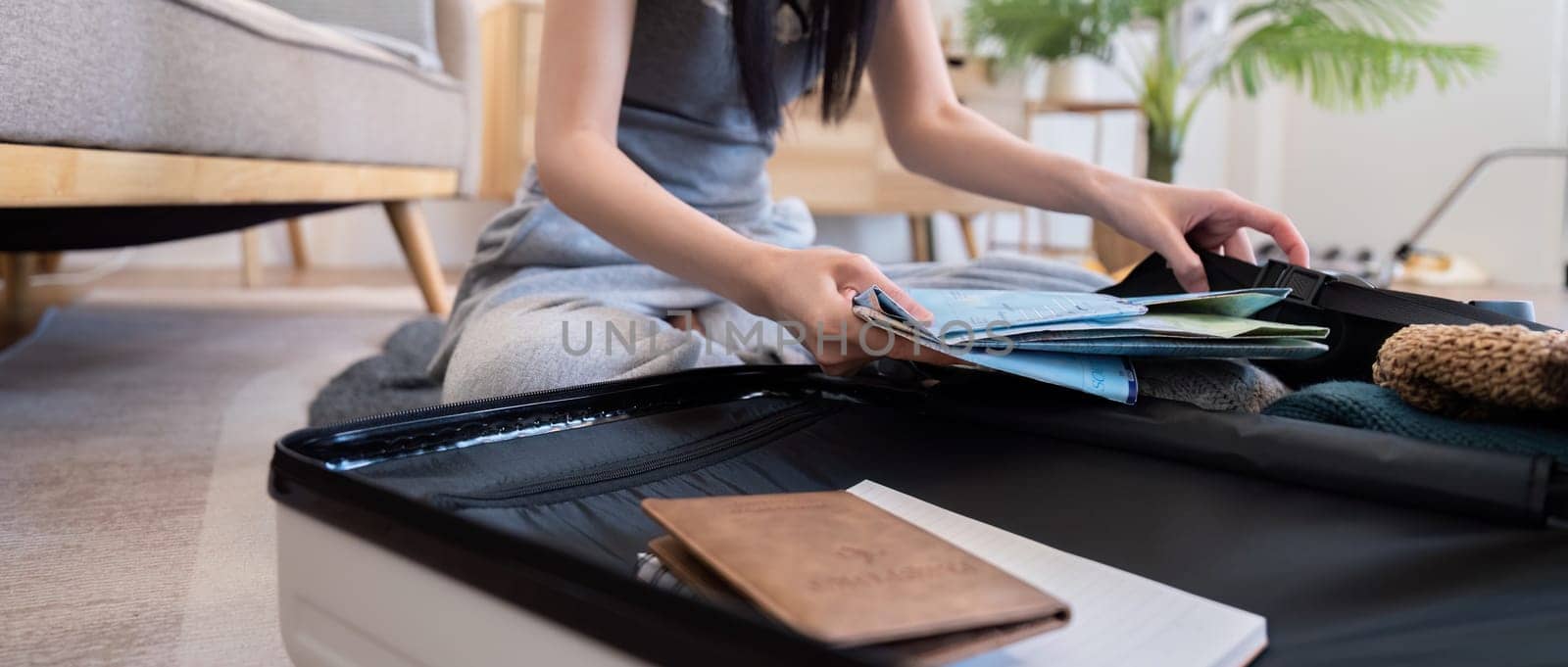 Young woman packing suitcase at home. Travel concept.