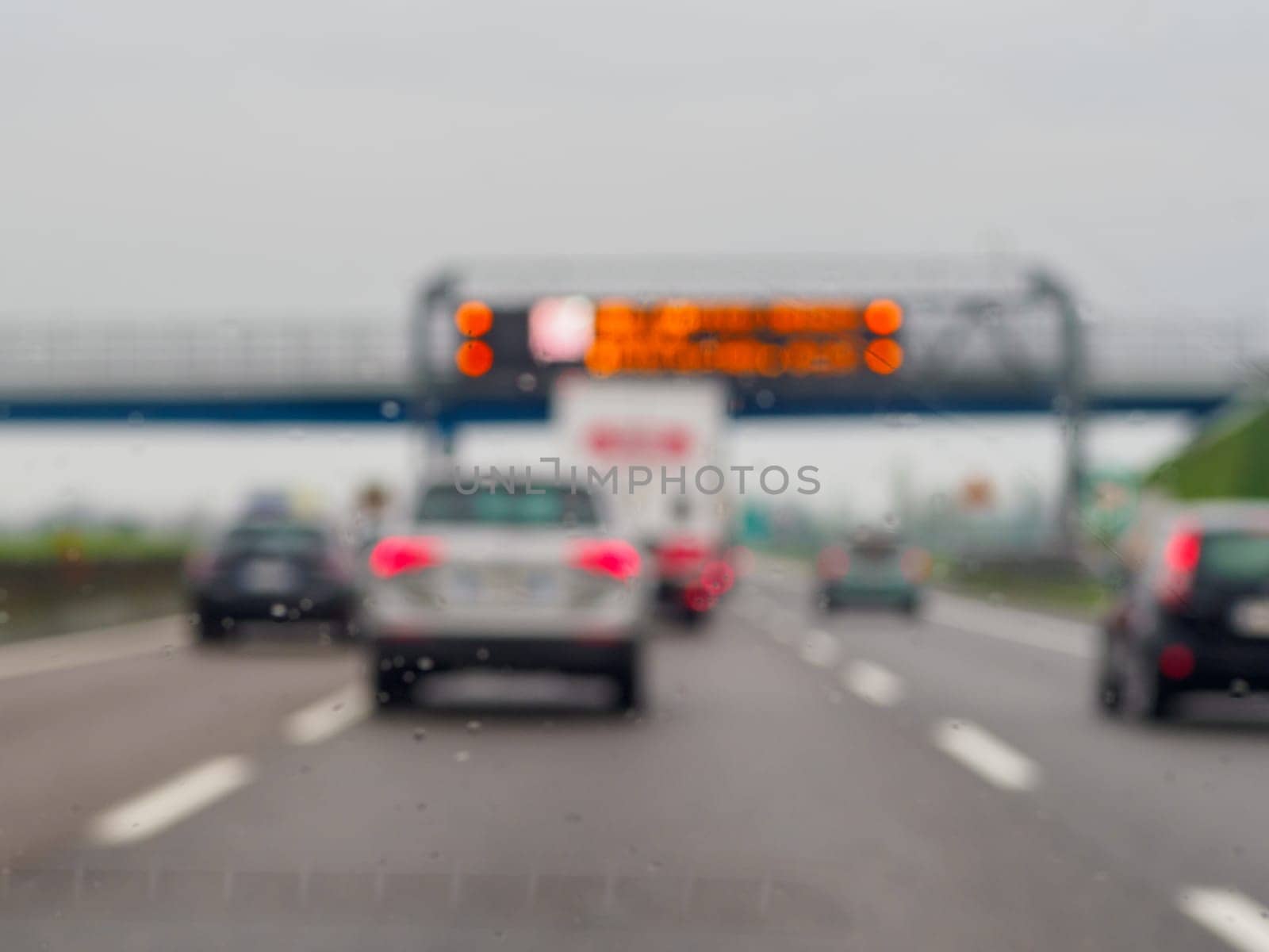 A blurry image of a busy highway with cars and a truck. The cars are moving at a slow pace and the truck is in the middle of the road