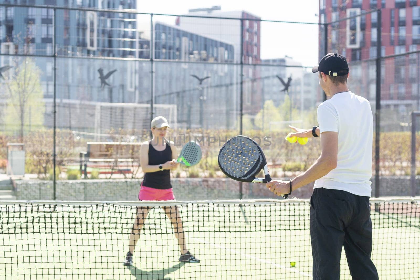 Sports couple with padel rackets posing on tennis court. High quality photo