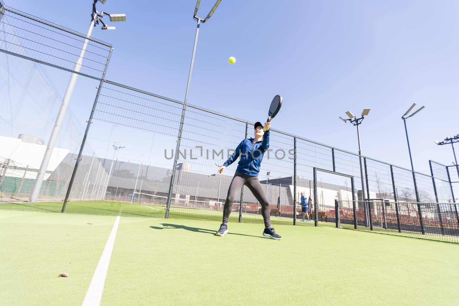 Determined sporty young woman playing padel in court. High quality photo
