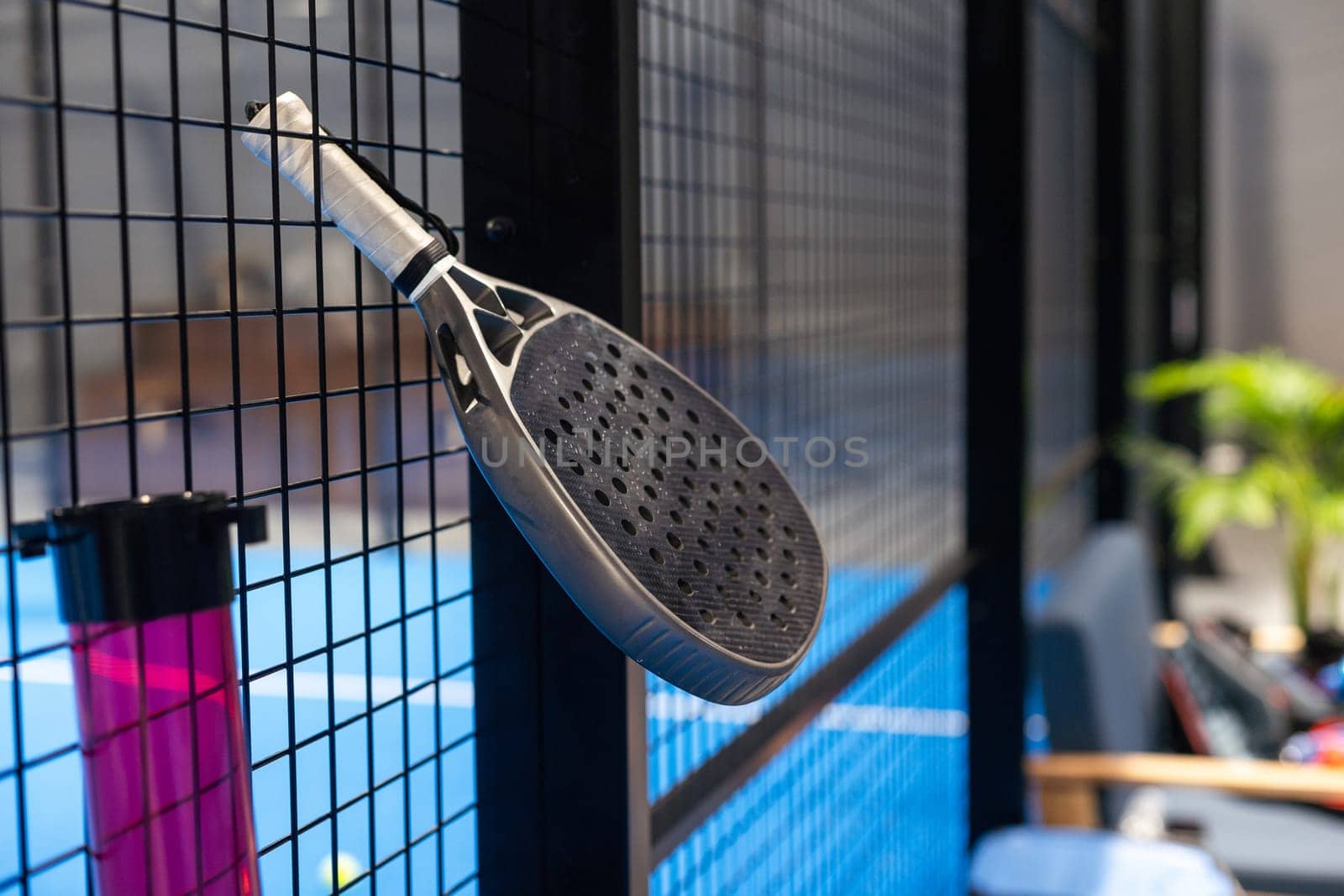 Black professional paddle tennis racket and ball with natural lighting on blue background. Horizontal sport theme poster, greeting cards, headers, website and app. High quality photo