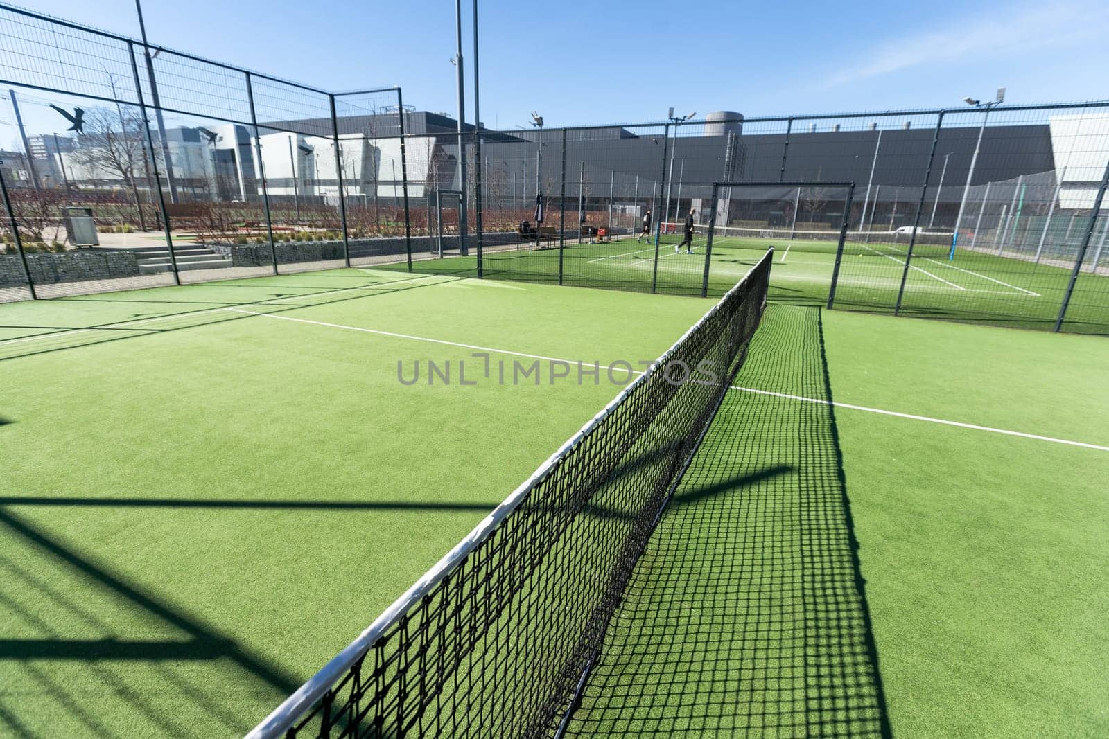 Landscaped areas of a residential development with a tennis court with high Plexiglas and metal fences. High quality photo