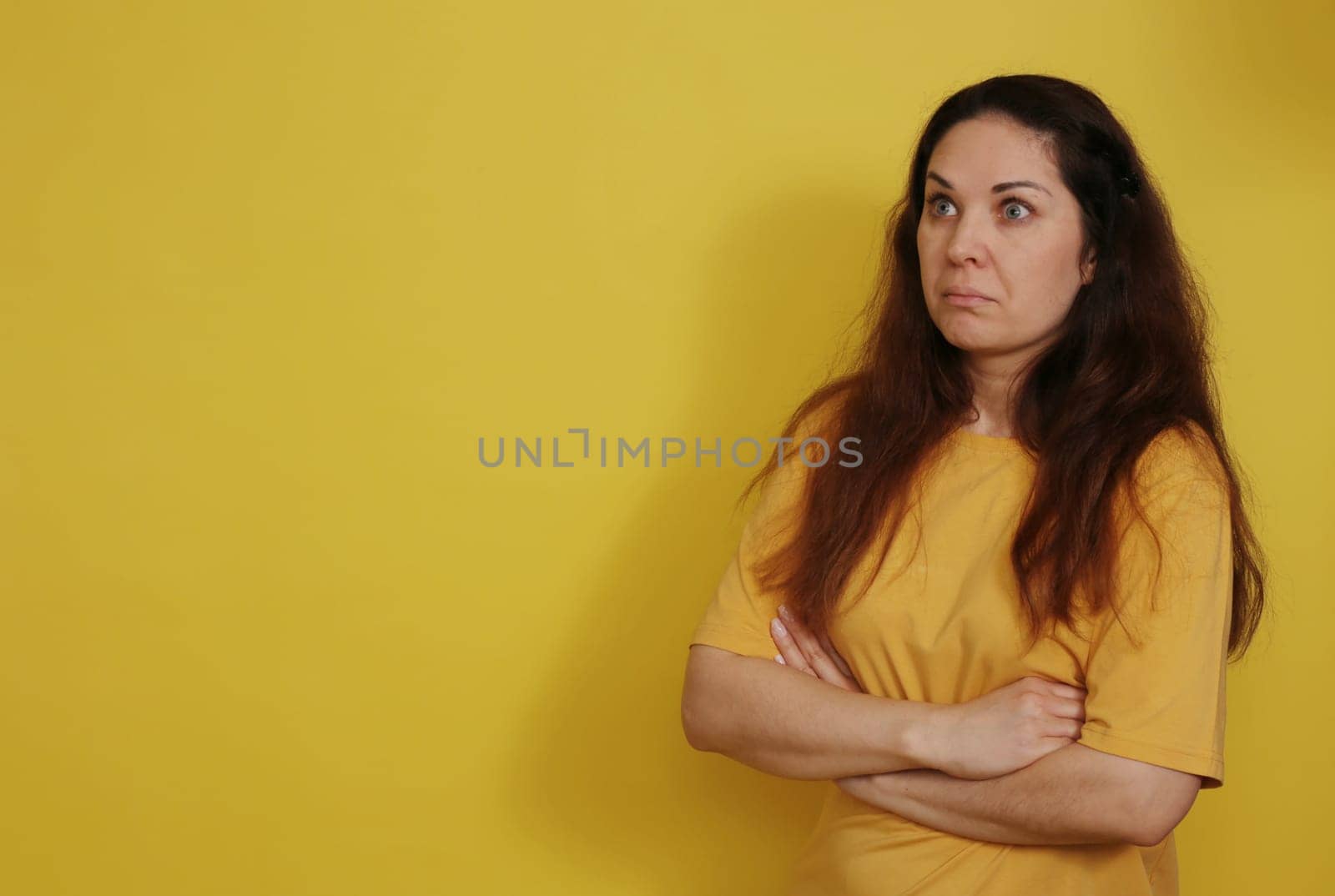 A pretty brunette woman in a yellow T-shirt in a state of bewilderment and consternation.