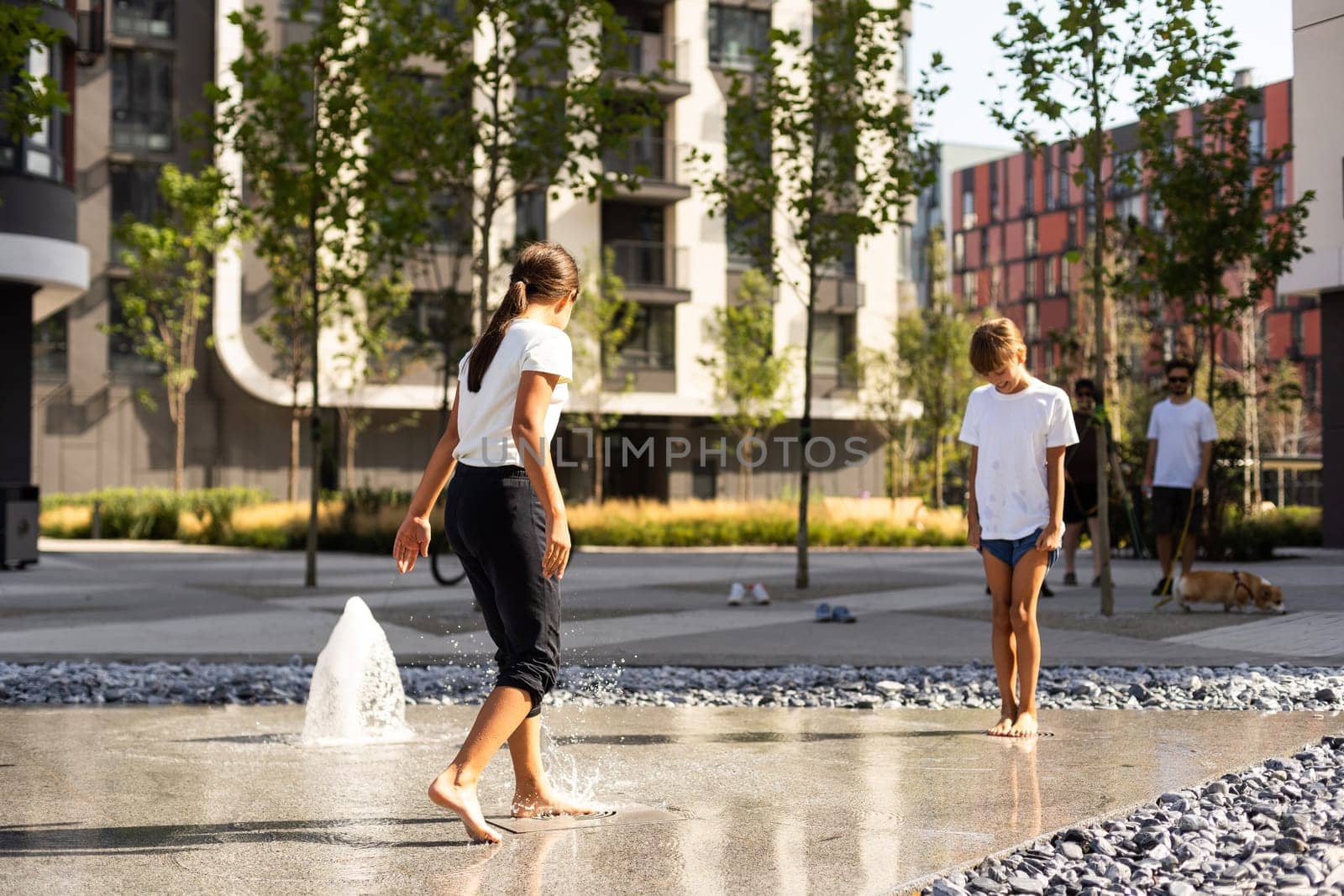 Little girls cool off in a fountain on a hot summer day. High quality photo