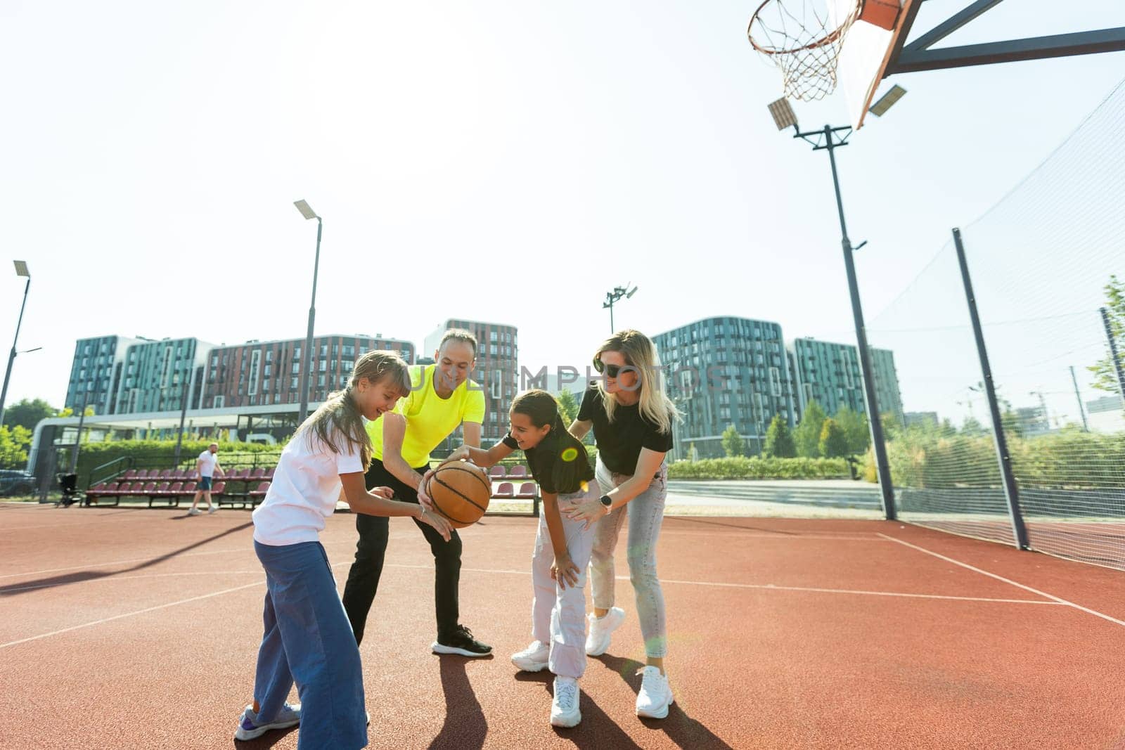 summer holidays, sport and people concept - happy family with ball playing on basketball playground. High quality photo