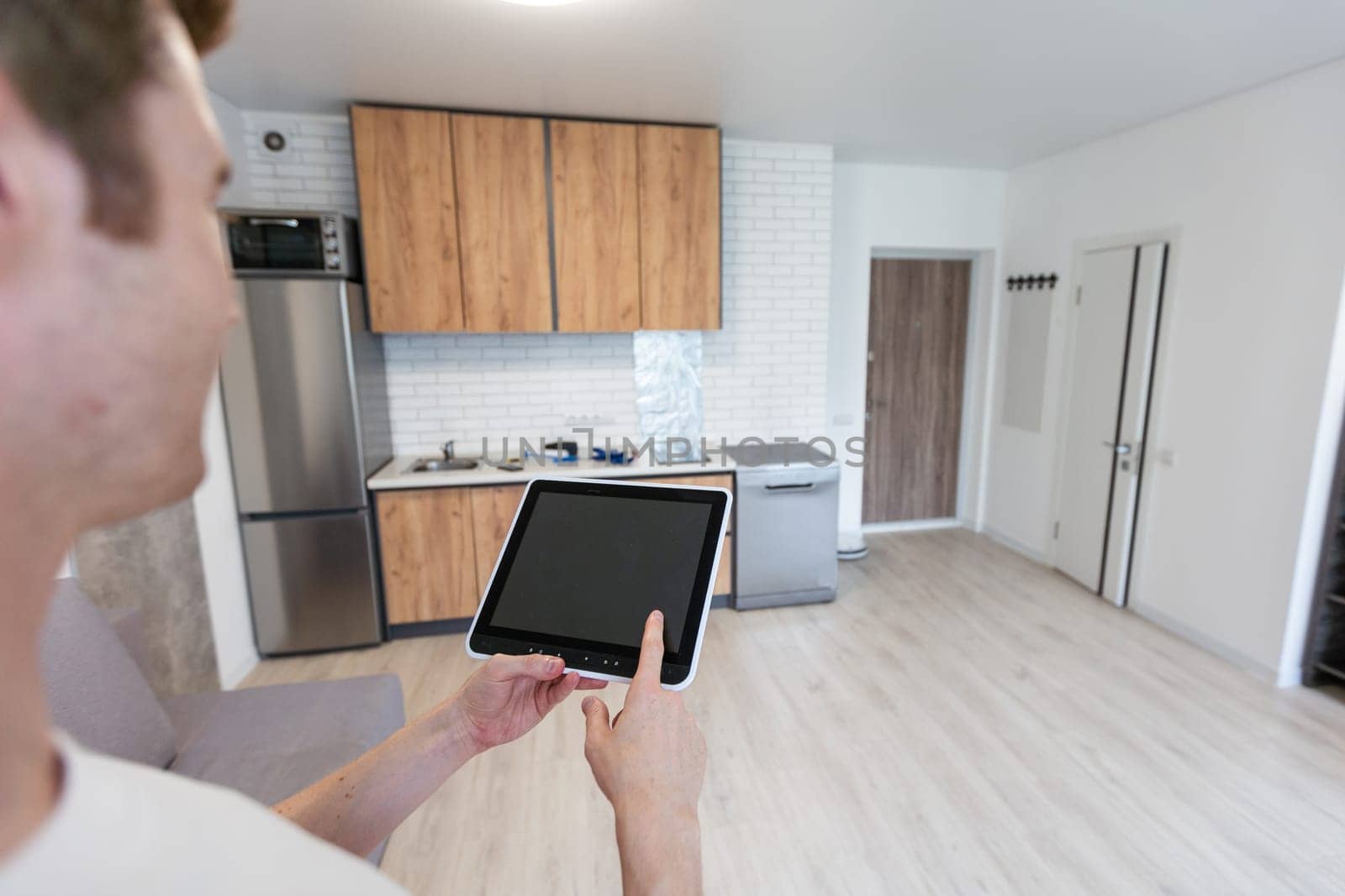 Worker with tablet computer checking alarm system indoors. by Andelov13