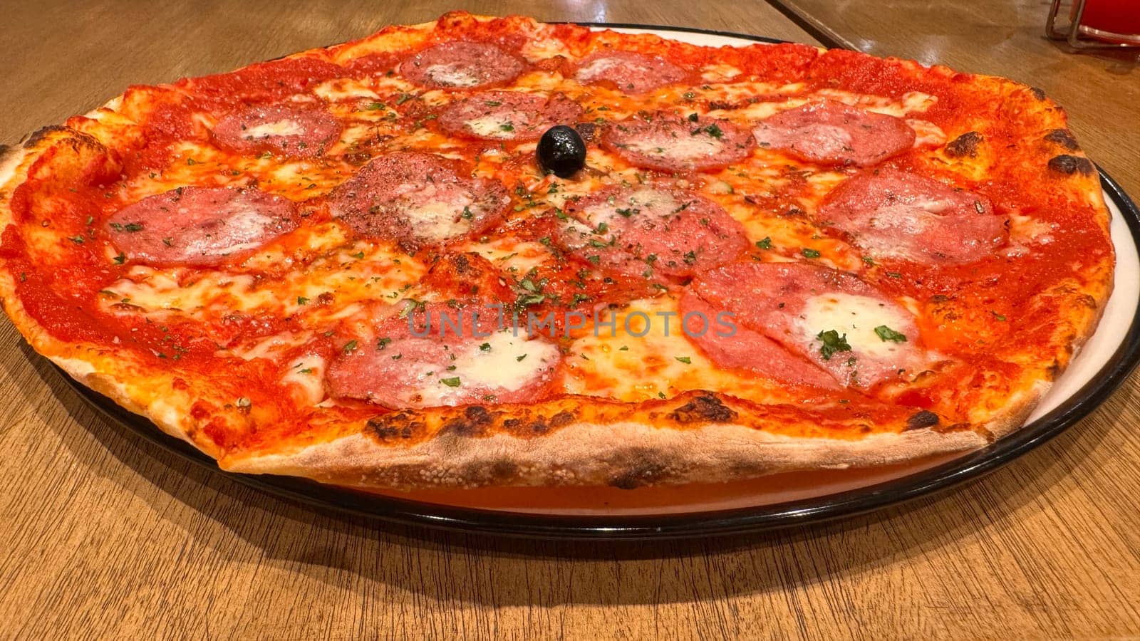 Freshly baked New York style pizza with melted mozzarella cheese and base tomato sauce close-up on a wooden board on the table. with lots of pepperoni