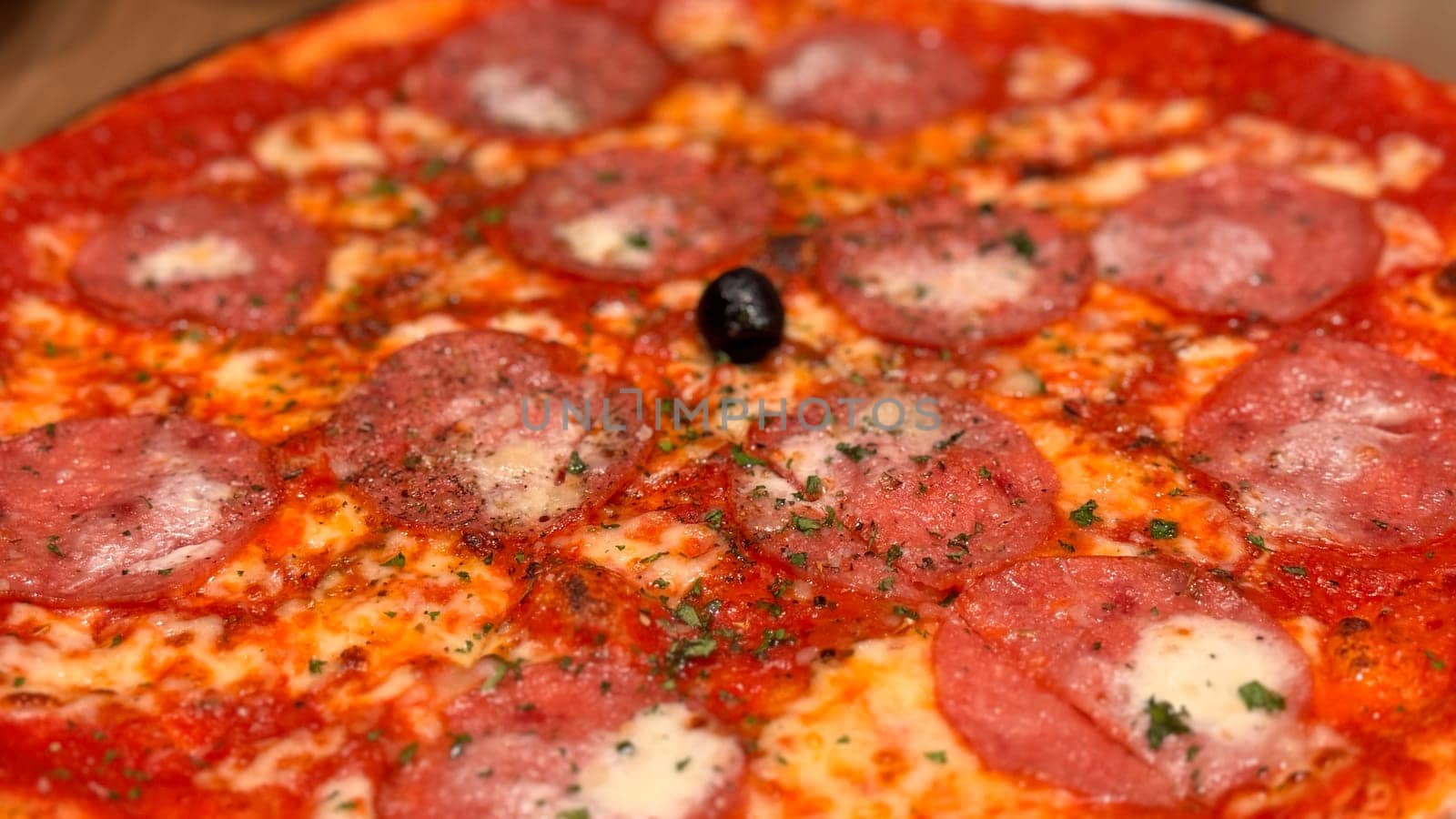 Freshly baked New York style pizza with melted mozzarella cheese and base tomato sauce close-up on a wooden board on the table. with lots of pepperoni