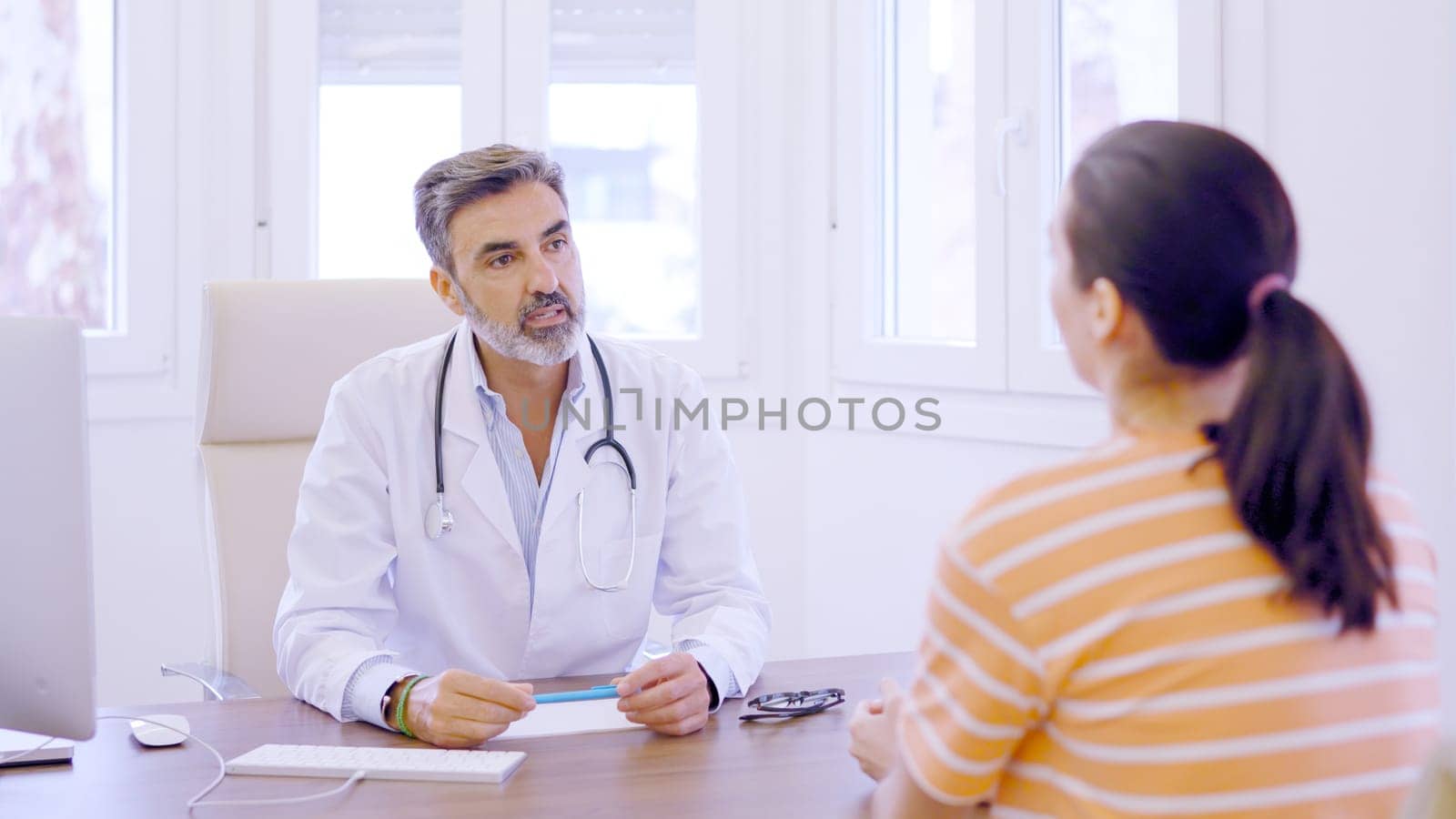 Woman entering to a clinic and sitting then greeting the doctor and start to explain symptoms in a clinic